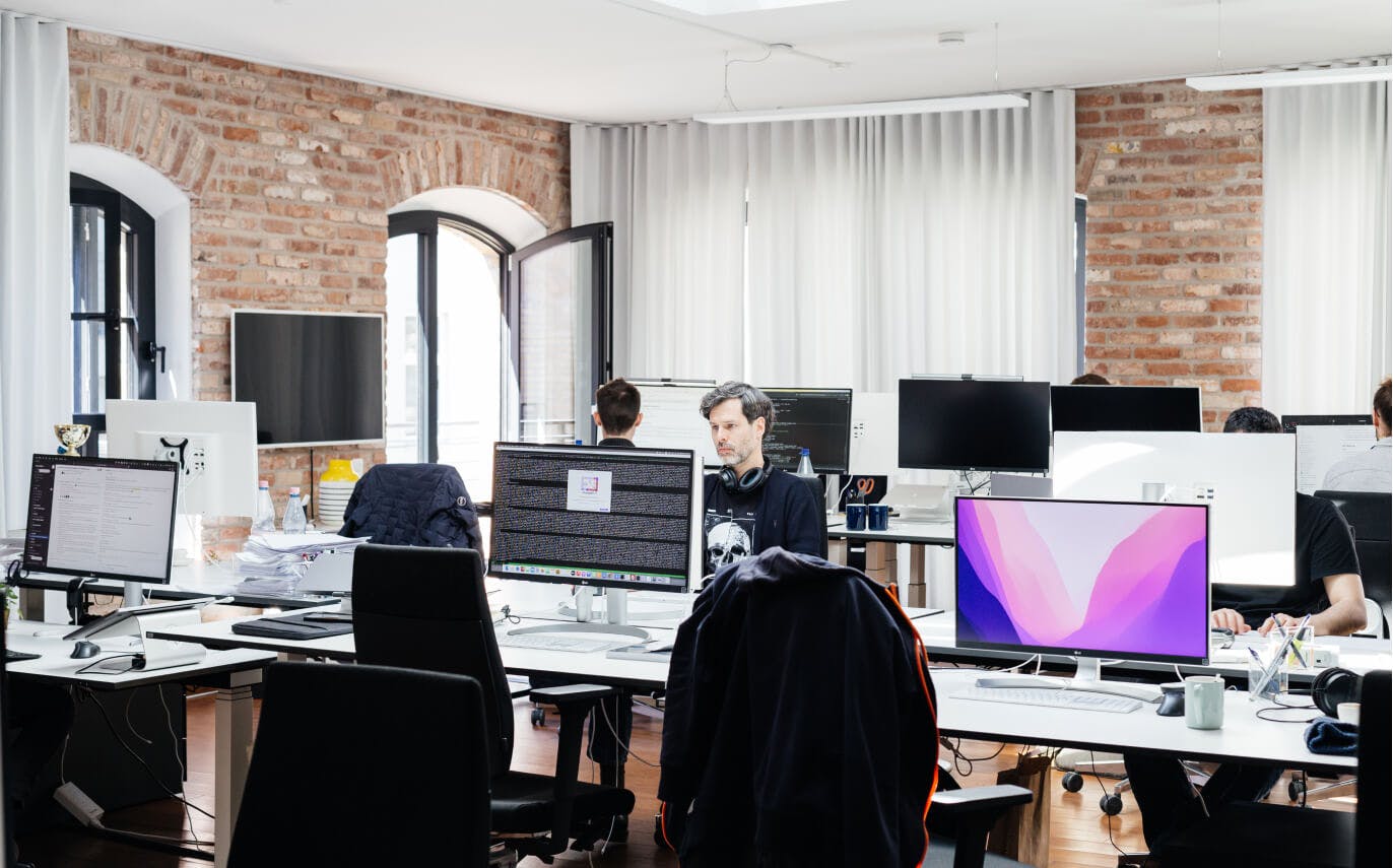 Der mit Computerbildschirmen und Mitarbeitern gefüllte Hauptraum im Berliner Büro.