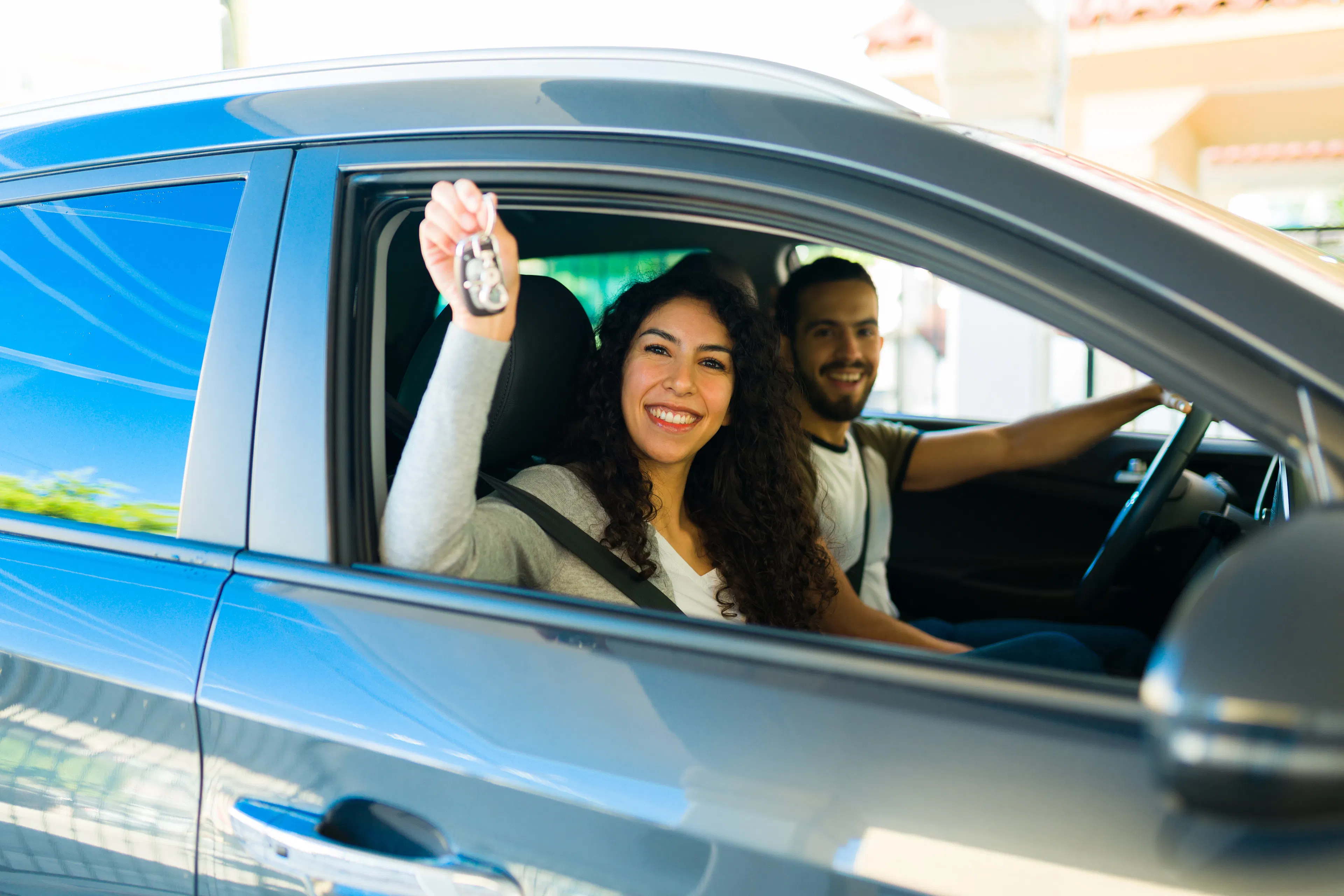 Excited young couple looking cheerful showing the keys after buying a new car