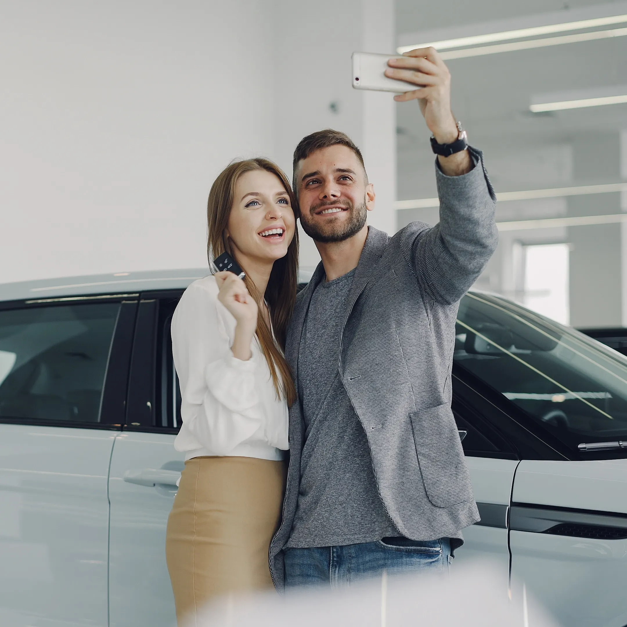 Happy couple taking a selfie showing up their brand new car