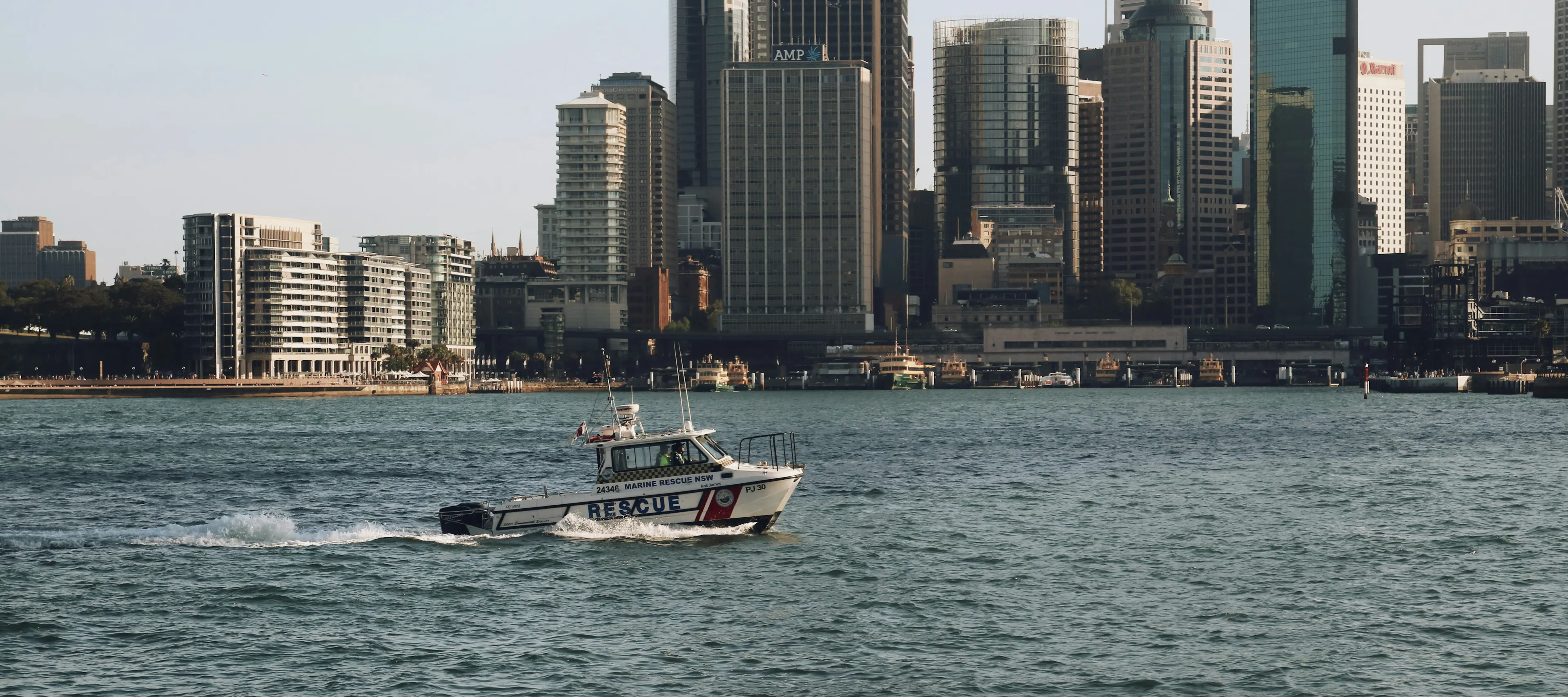 Rescue boat moving forward in the sea with high buildings in the city in the background