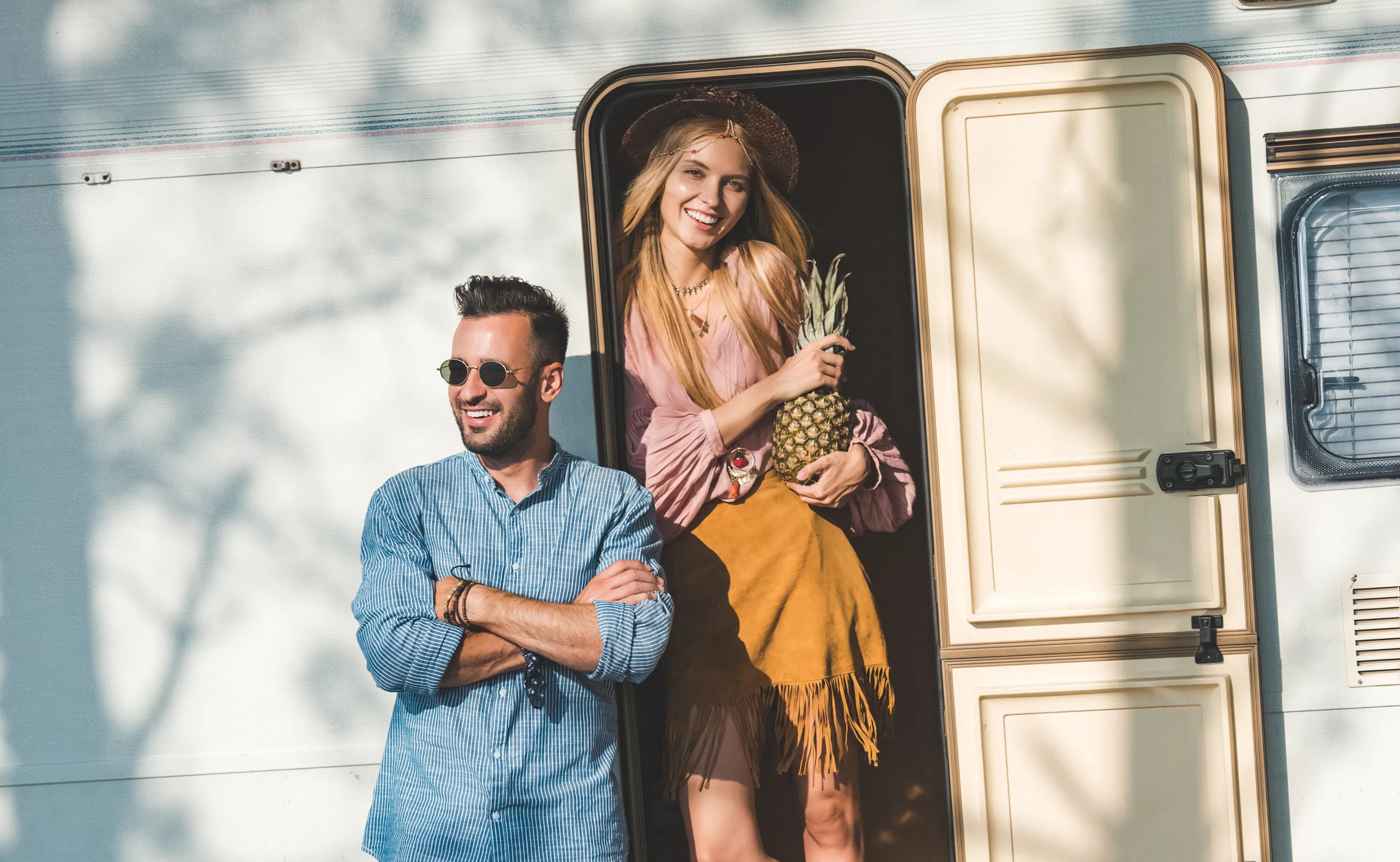 beautiful hippie couple with pineapple posing near campervan