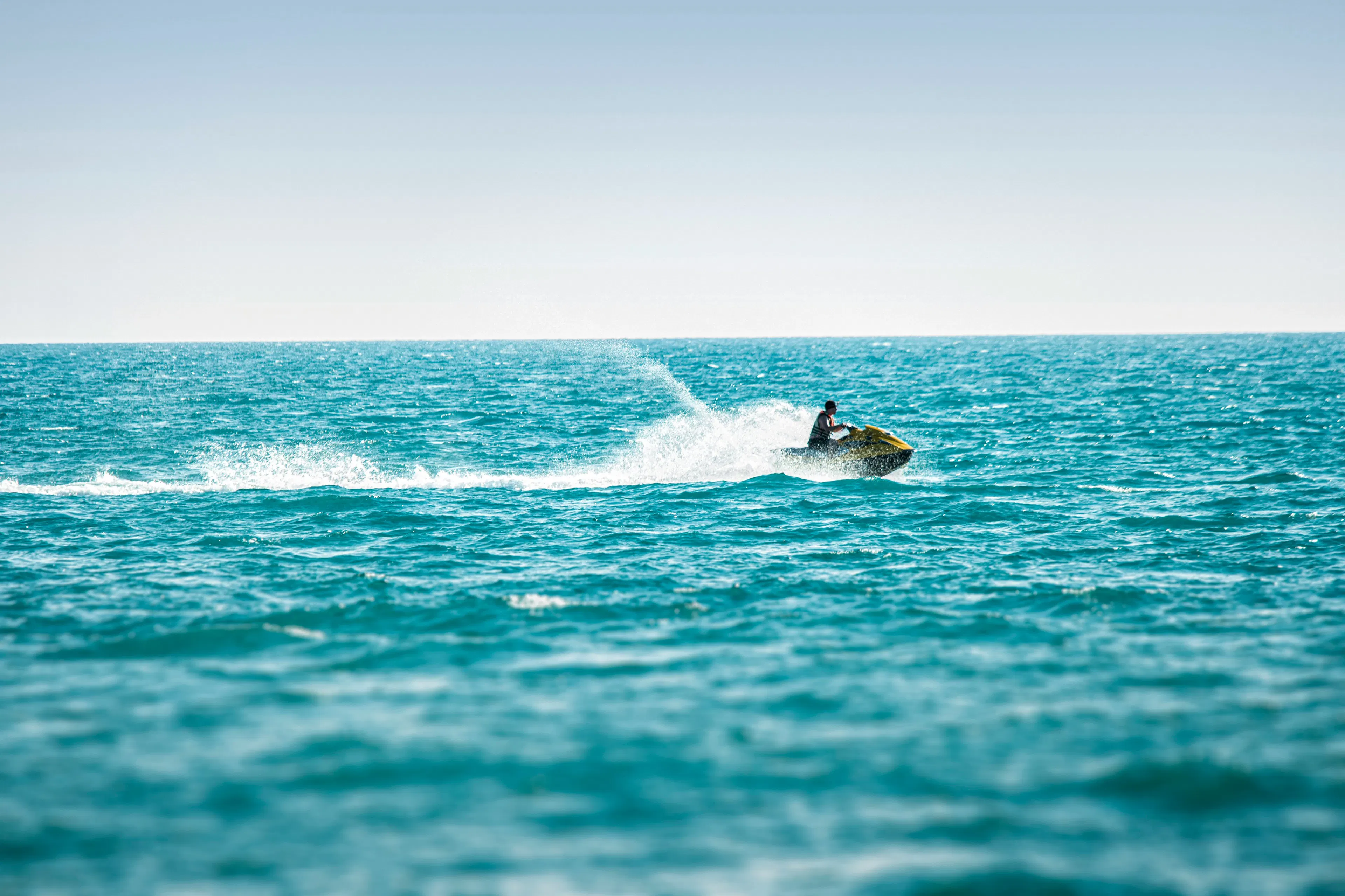 Person driving a jet ski in a blue sea