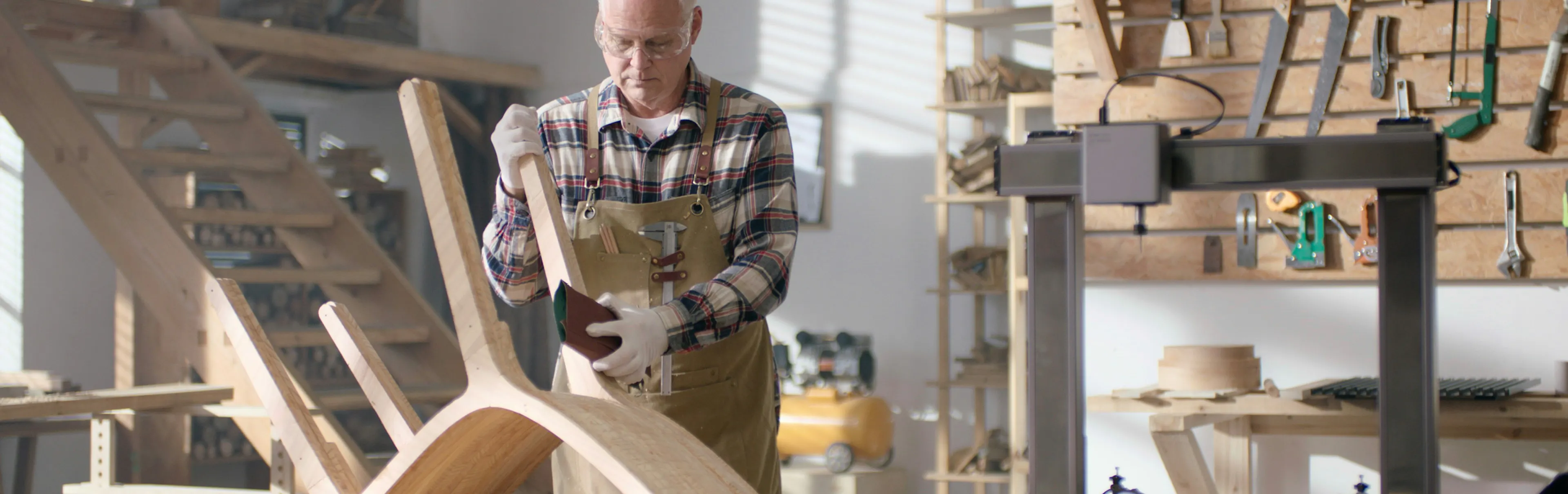 business owner worried about their finance while sanding a chair in their workshop