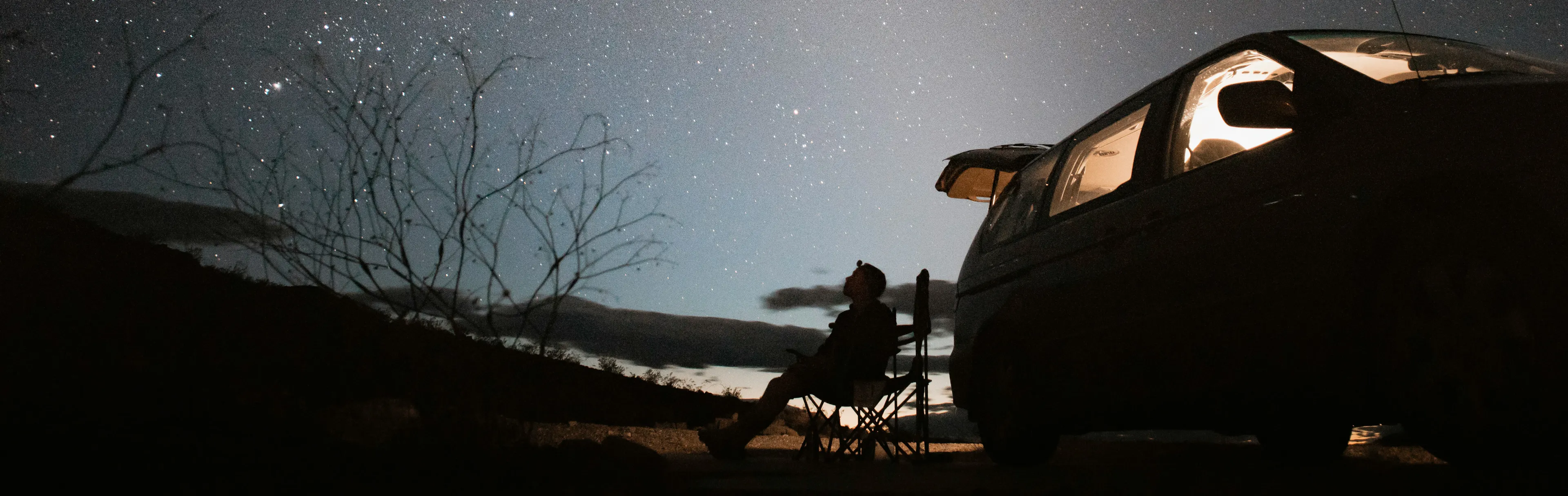 Person camping in their car at night