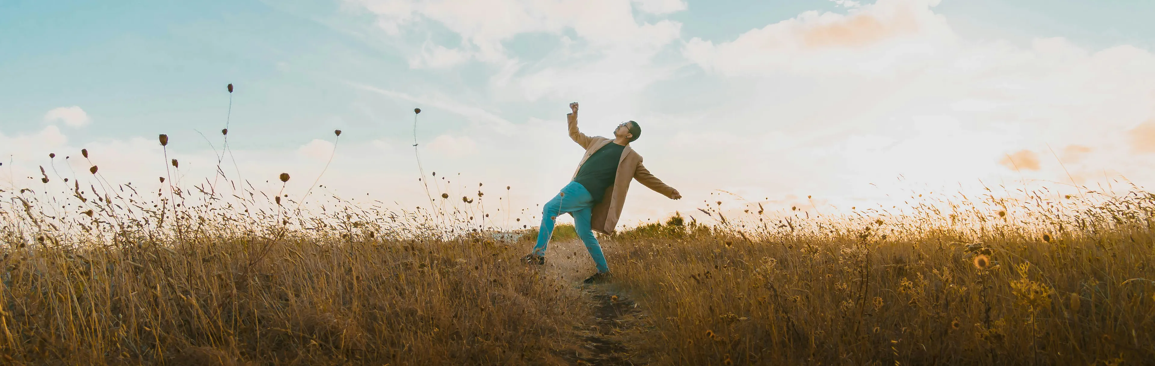 Young male dancing in green field