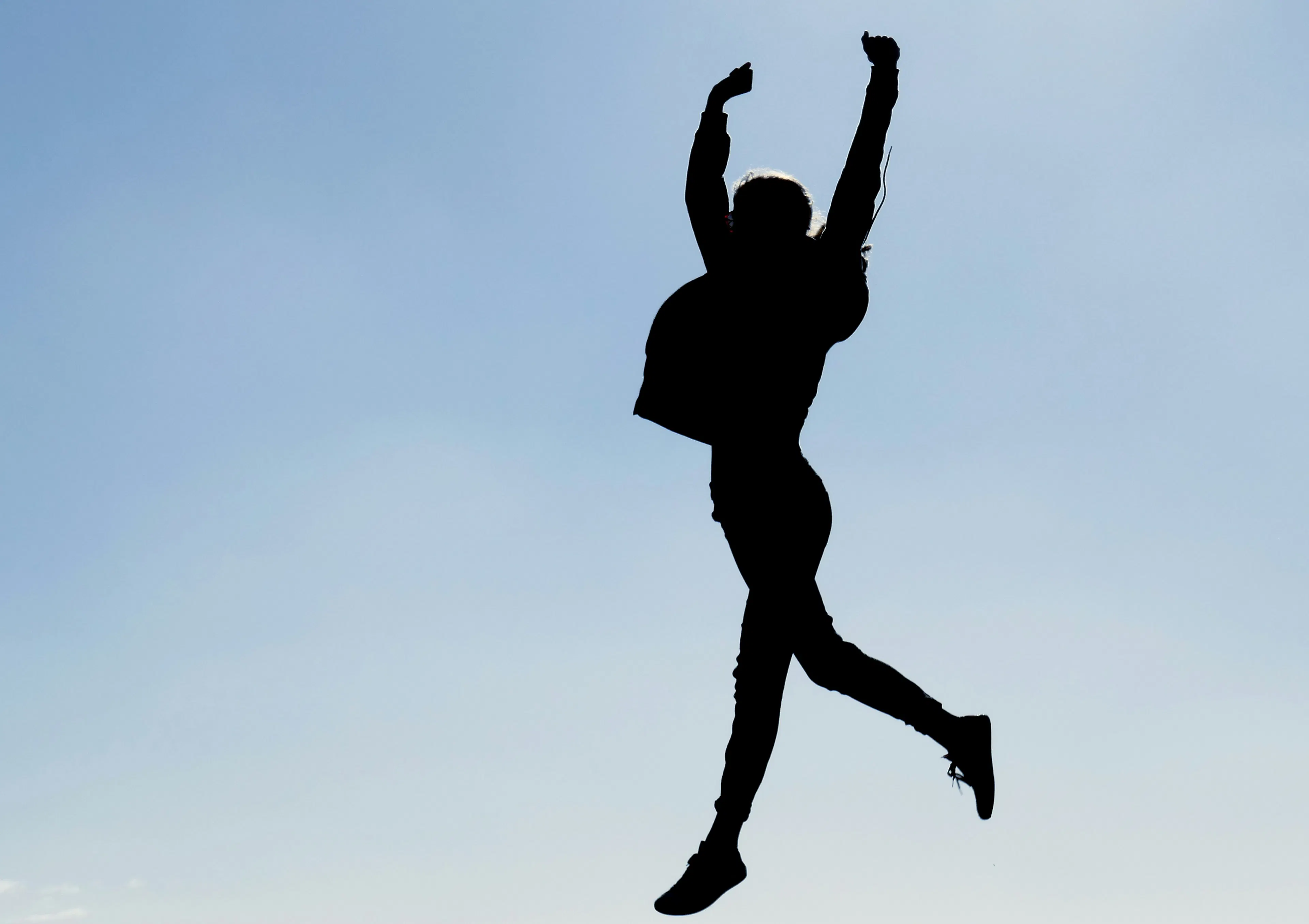 Happy person jumping high with the sky in the background
