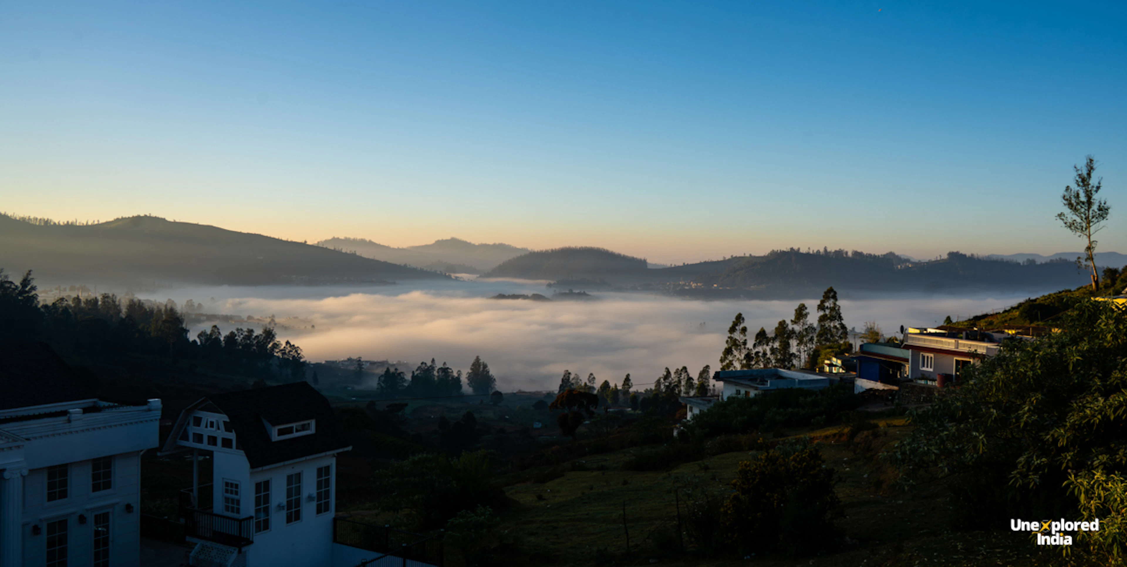 Ooty homestay overlooking mist-covered hills and valleys in the Nilgiris at sunrise.