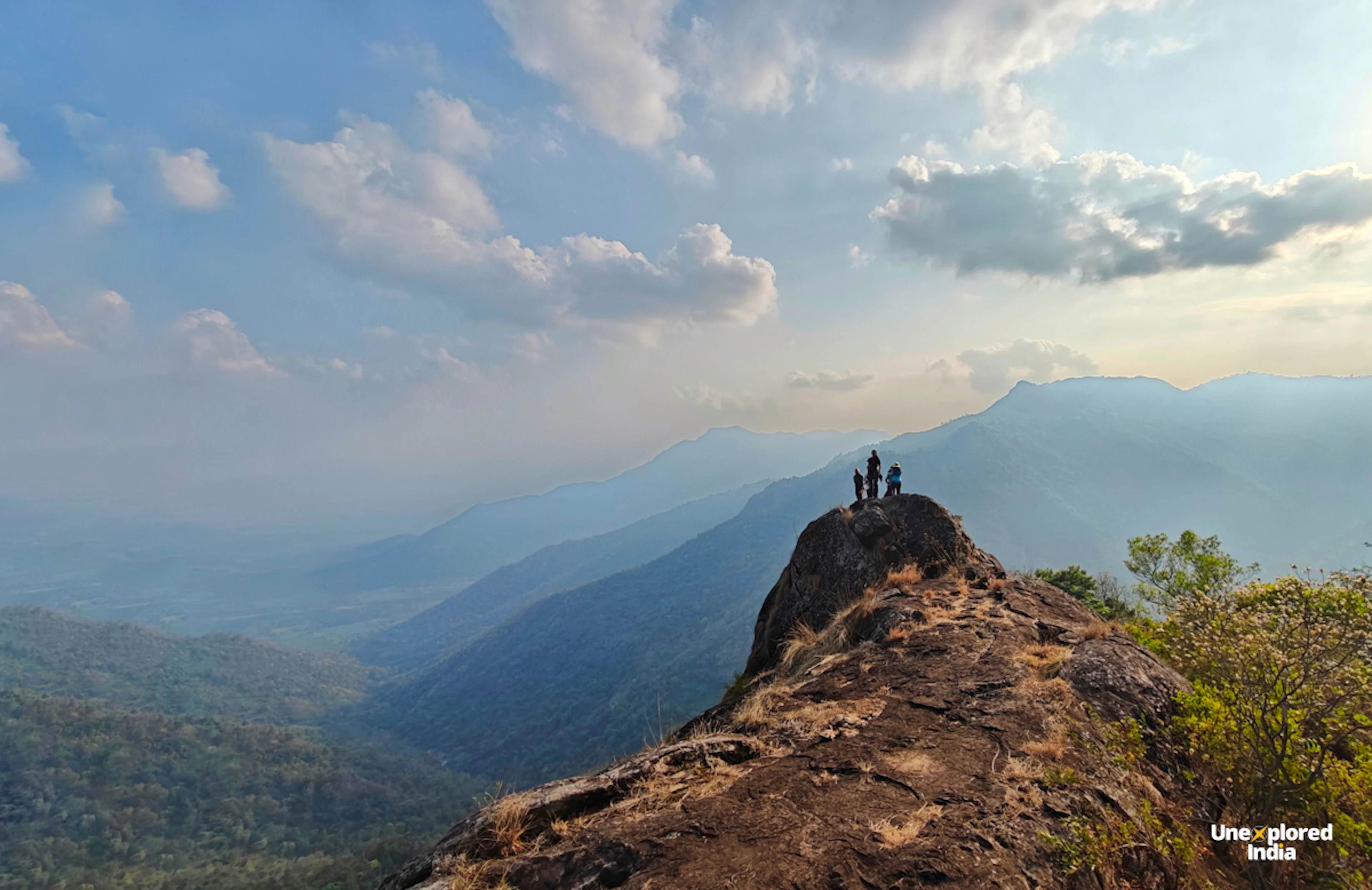 Hikers on a rocky cliff overlooking the Nilgiris and surrounding shola forests