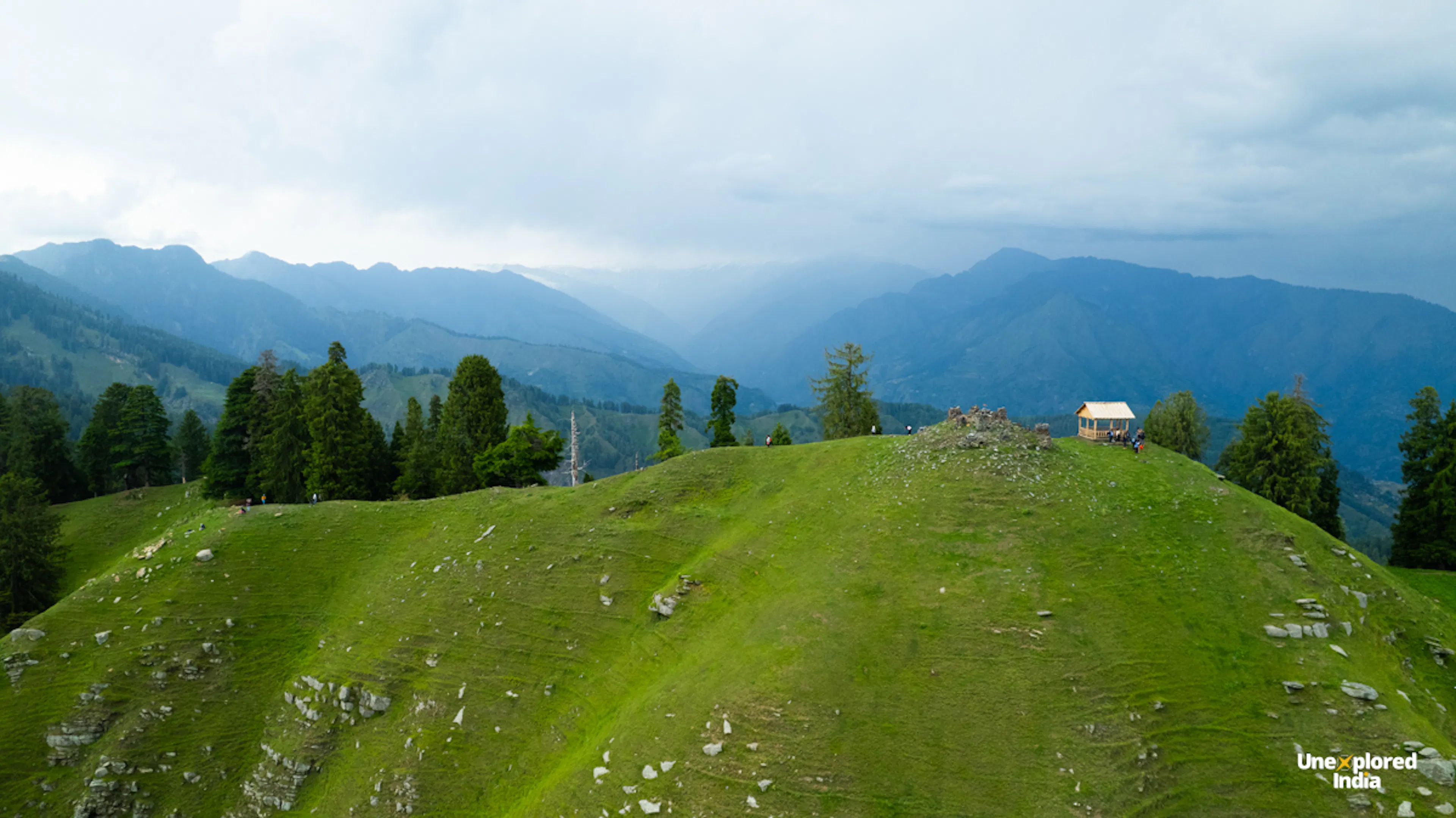Himachal Pradesh villages and grasslands near Kaisdhar, with mountain temple architecture and Dhauladhar range views