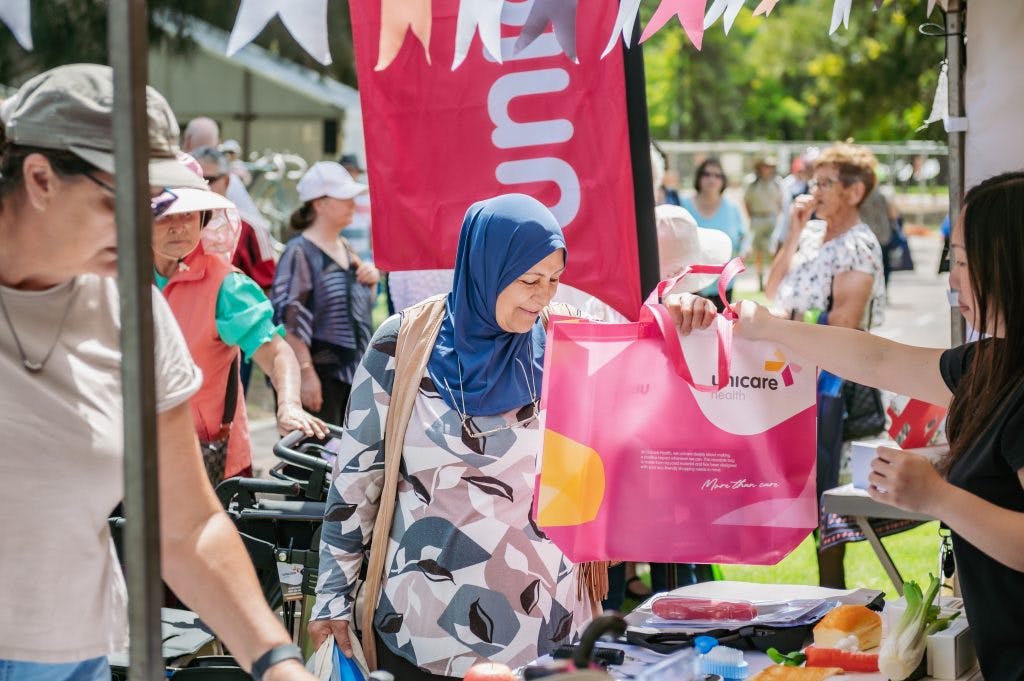 Seniors receive gift bags from Unicare Health's independent living aid display at Have A Go Day Burswood 2023