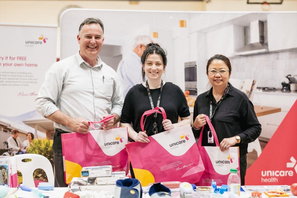 Unicare Health team poses with showbags at Rockingham Seniors and Carers Expo 2023