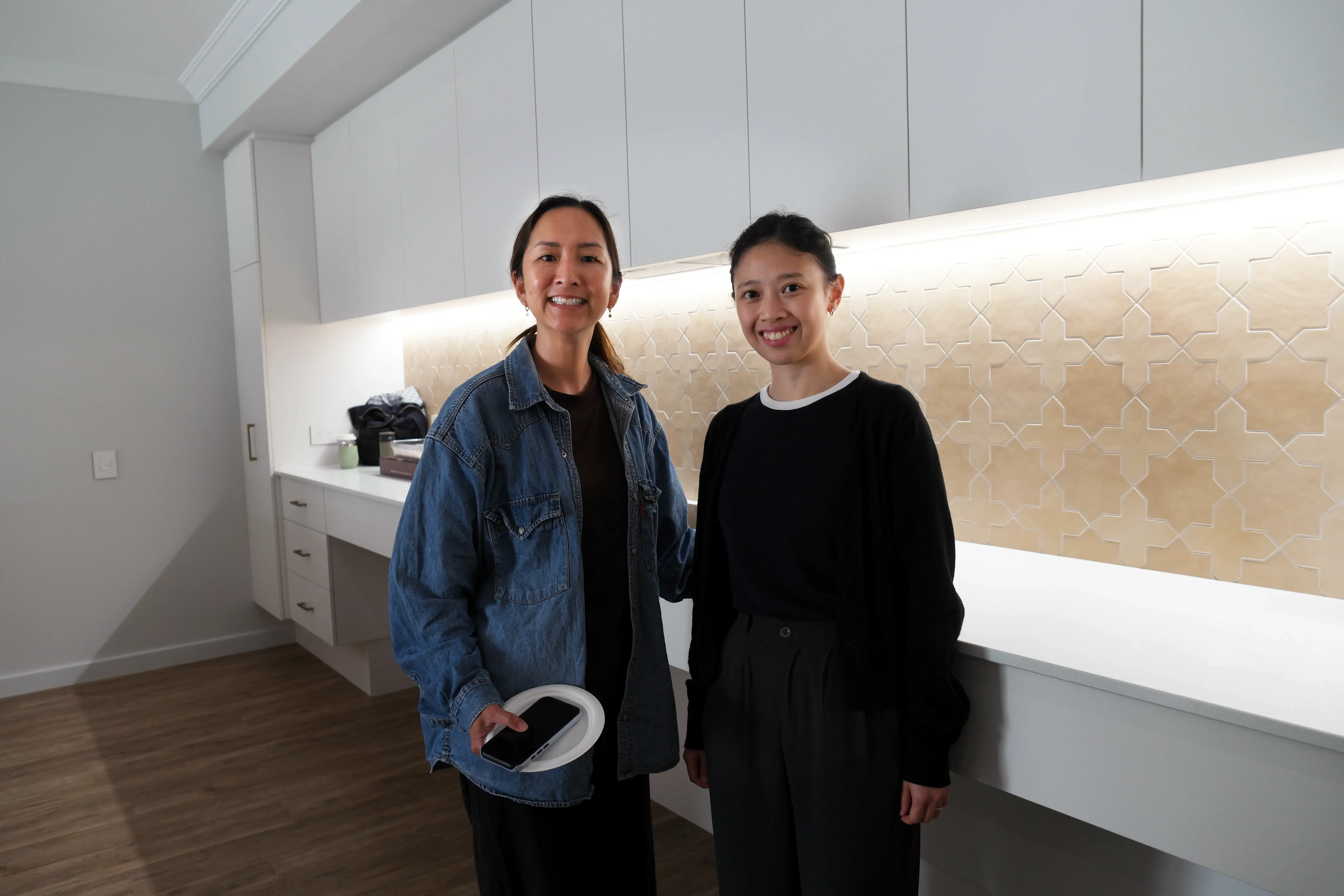 Our sleep surfaces educator Samantha and a participant smiling for a photograph in the kitchen area of the Sana Living demonstration home in Atwell.