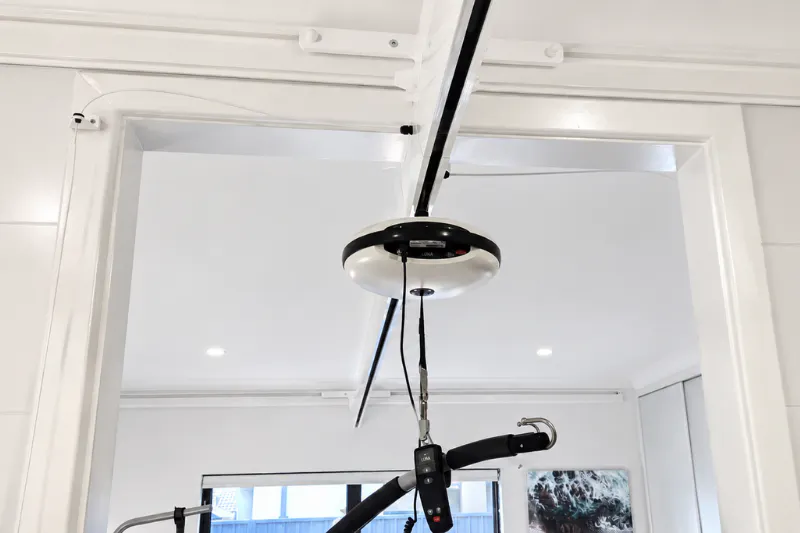 Wall-mounted ceiling hoist track with a transition gate connector above a doorway.