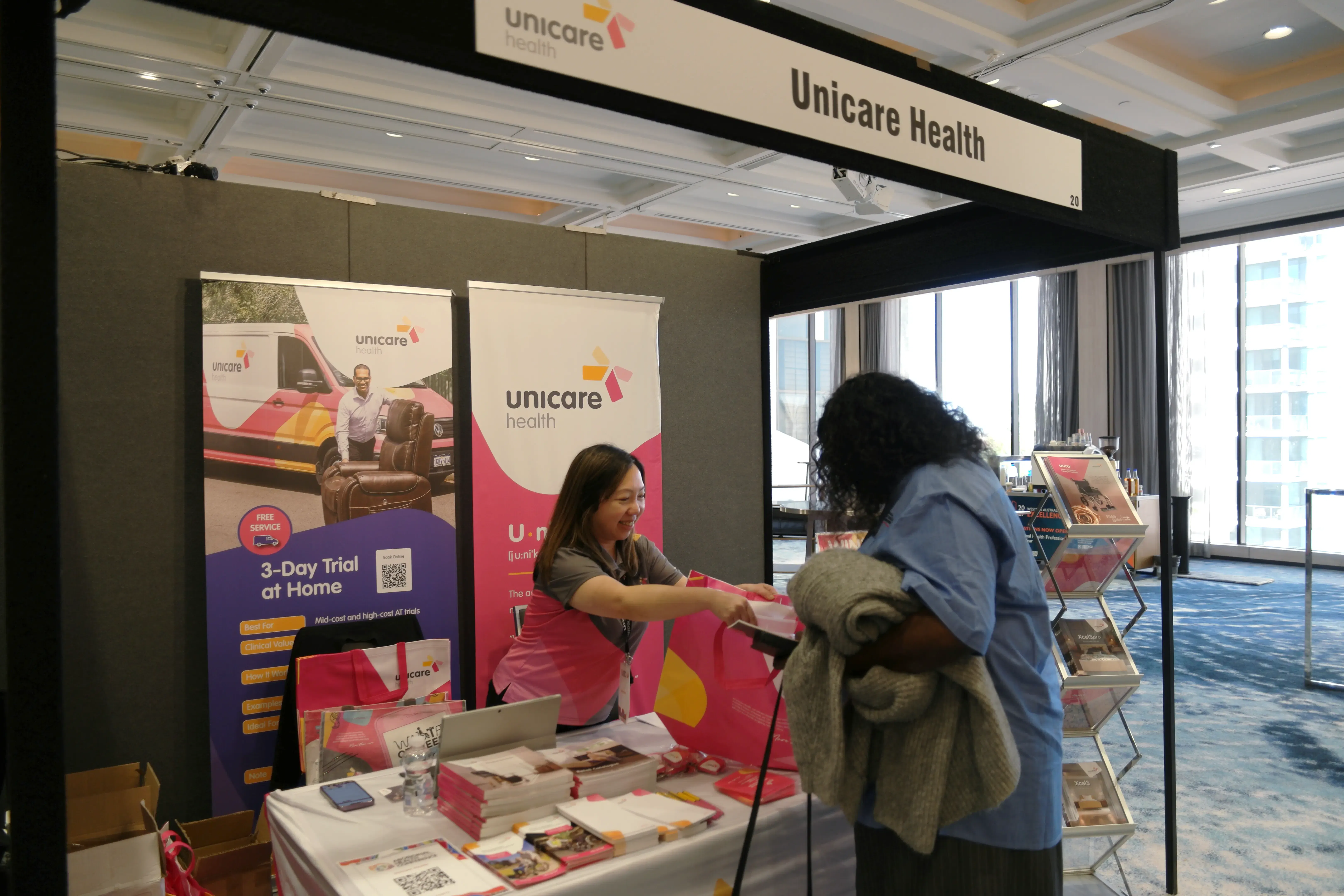 Pearl from Unicare Health handing a showbag to a delegate at the Aboriginal Health Conference 2026 in Perth.