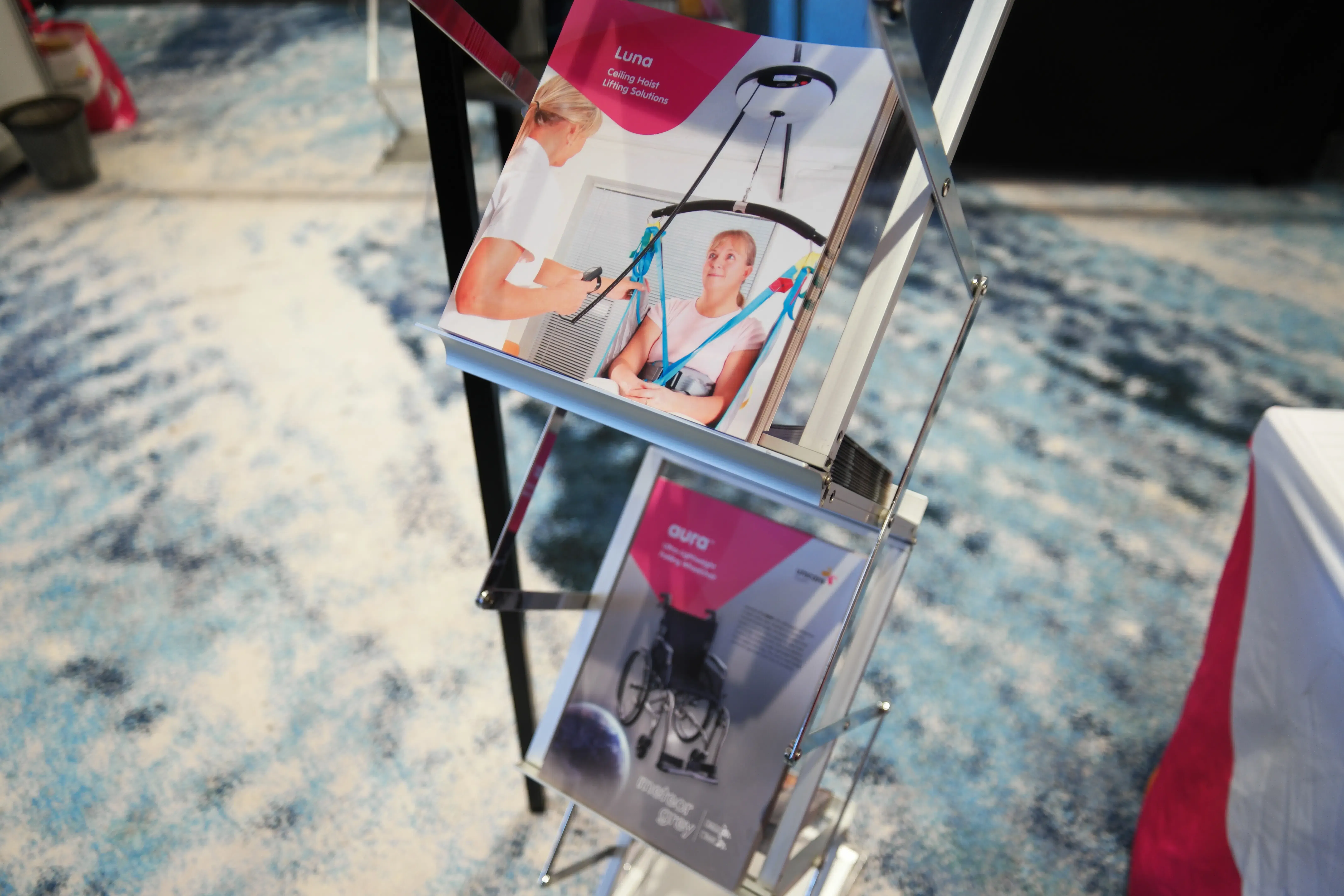 Unicare’s Luna ceiling hoist and Aura wheelchair catalogues displayed on a rack at the Aboriginal Health Conference 2026
