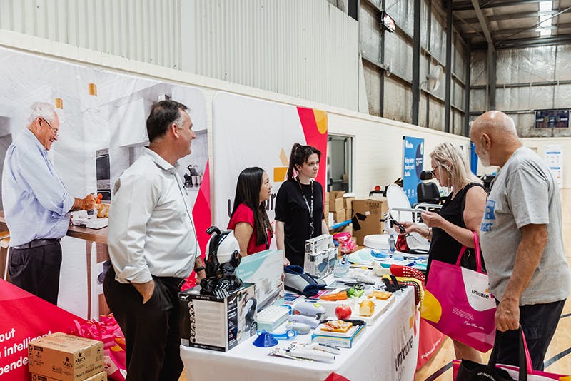 Seniors discuss home care daily living aids with Unicare Health at Have A Go Day Rockingham 2023
