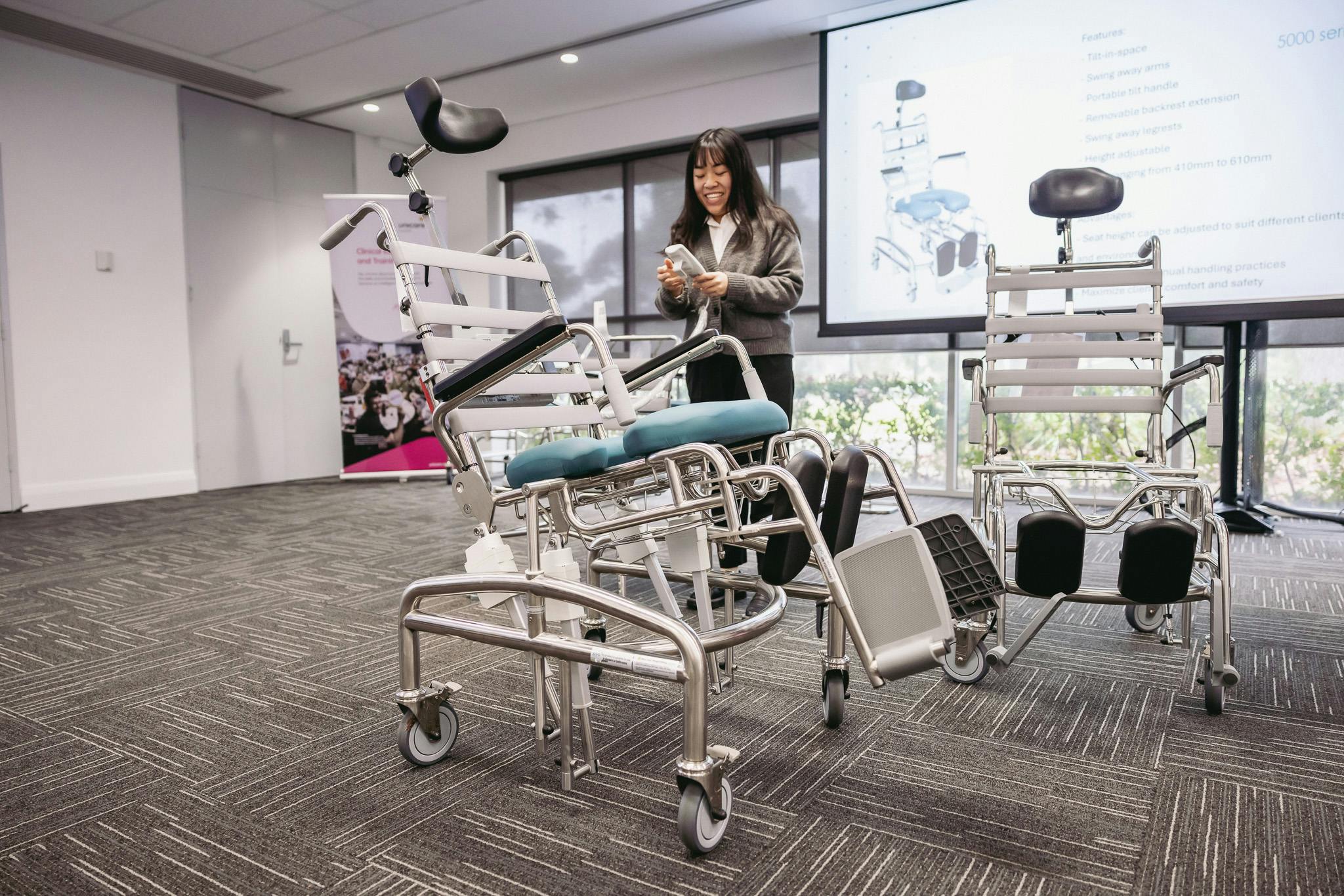 clinical educator tilts a tilt-in-space commode to a 45 degree angle using electric remote