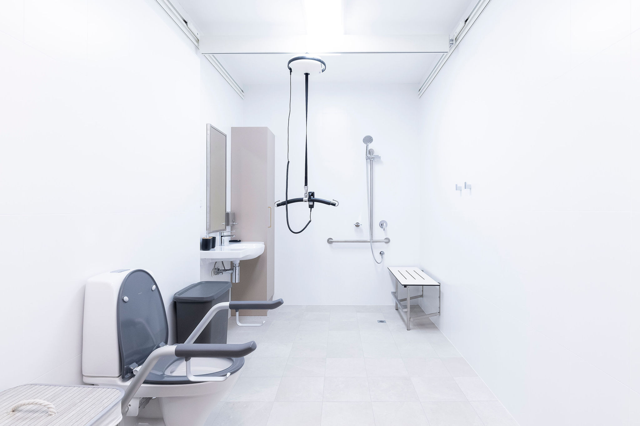 Fully accessible bathroom with ceiling hoist, shower bench and support rails at Lady Lawley Cottage Cottesloe, Perth disability accommodation