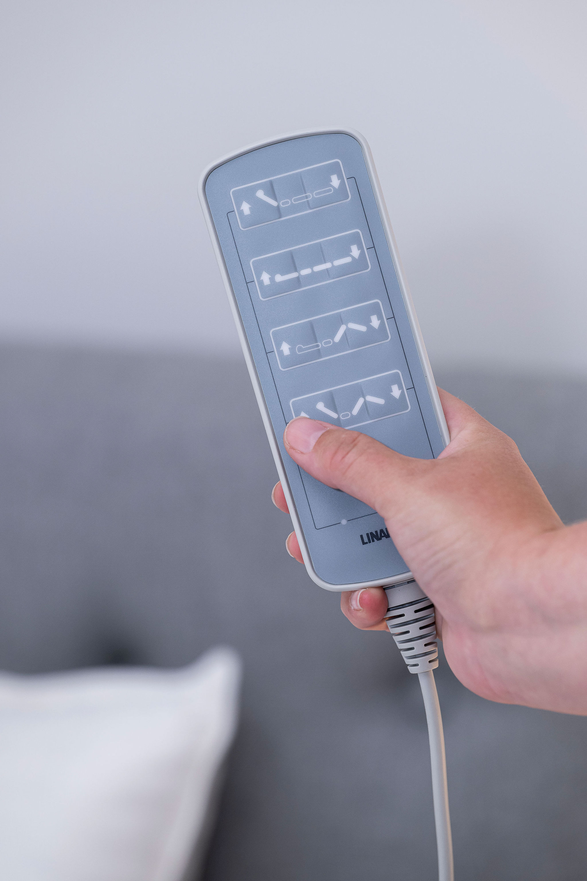 Hand holding electric adjustable bed remote control in accessible accommodation at Lady Lawley Cottage Cottesloe, Perth