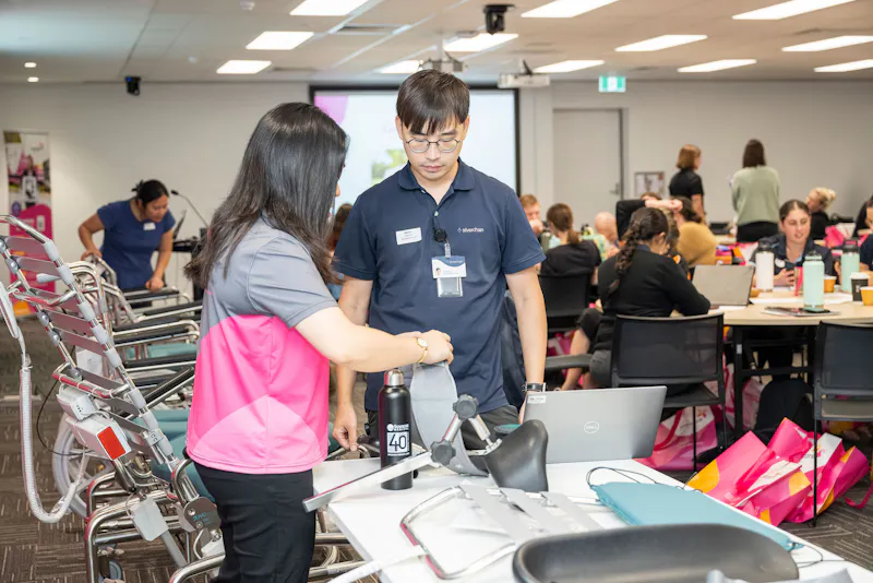 Unicare Health team demonstrating shower commode components and accessories to clinicians during bathroom mobility training workshop in Perth WA