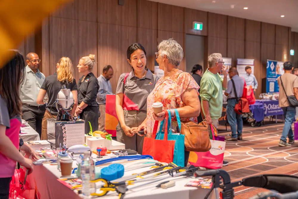 Attendees speaking with Unicare staff member at Bankstown Disability Expo NSW, exploring assistive equipment and support services at Canterbury League Club Belmore