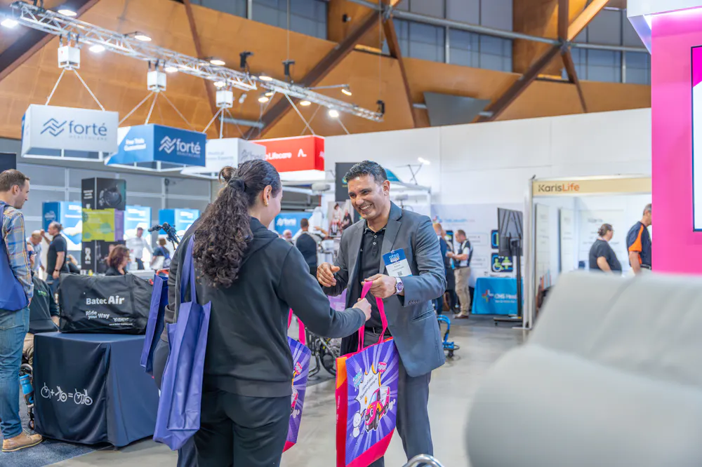 Unicare Health team member handing out showbags to attendees at the ATSA Independent Living Expo Sydney 2026.
