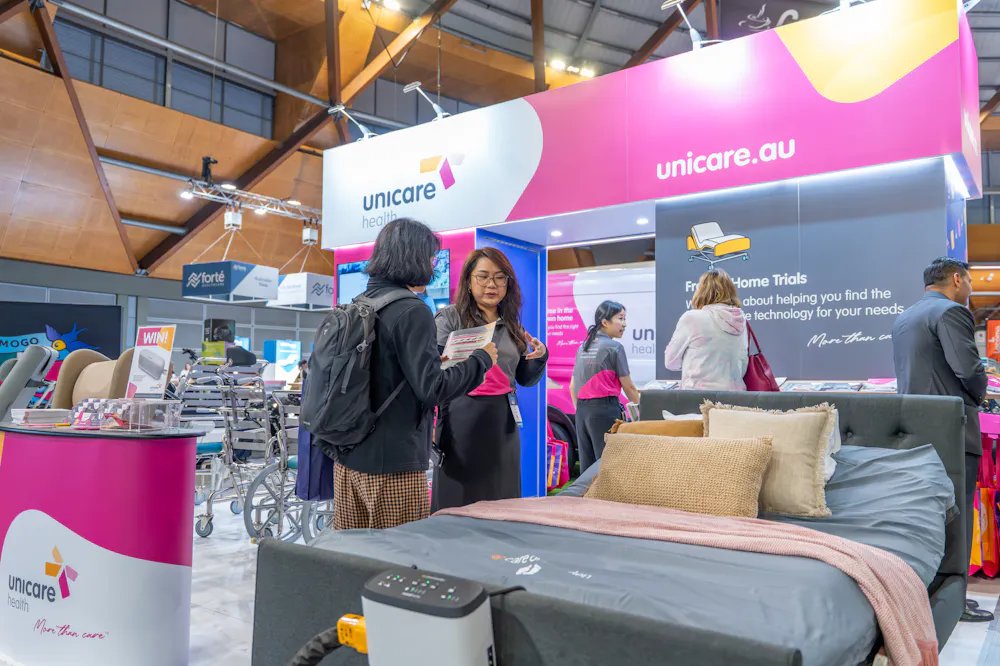 Visitors speaking with Unicare Health staff about pressure care and assistive technology at the ATSA Independent Living Expo Sydney 2026.