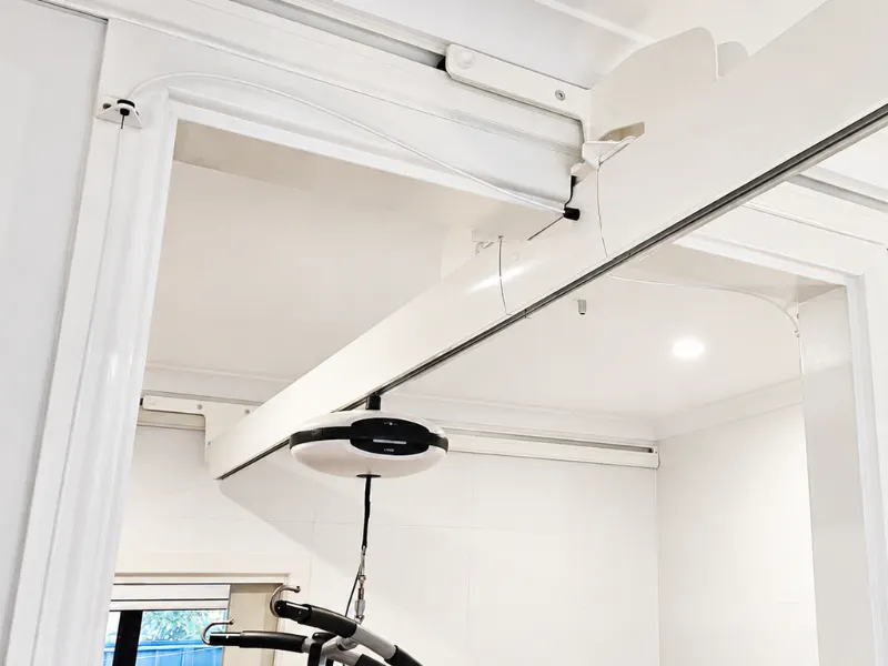 Wall-mounted ceiling hoist track with a transition gate connector above a doorway.