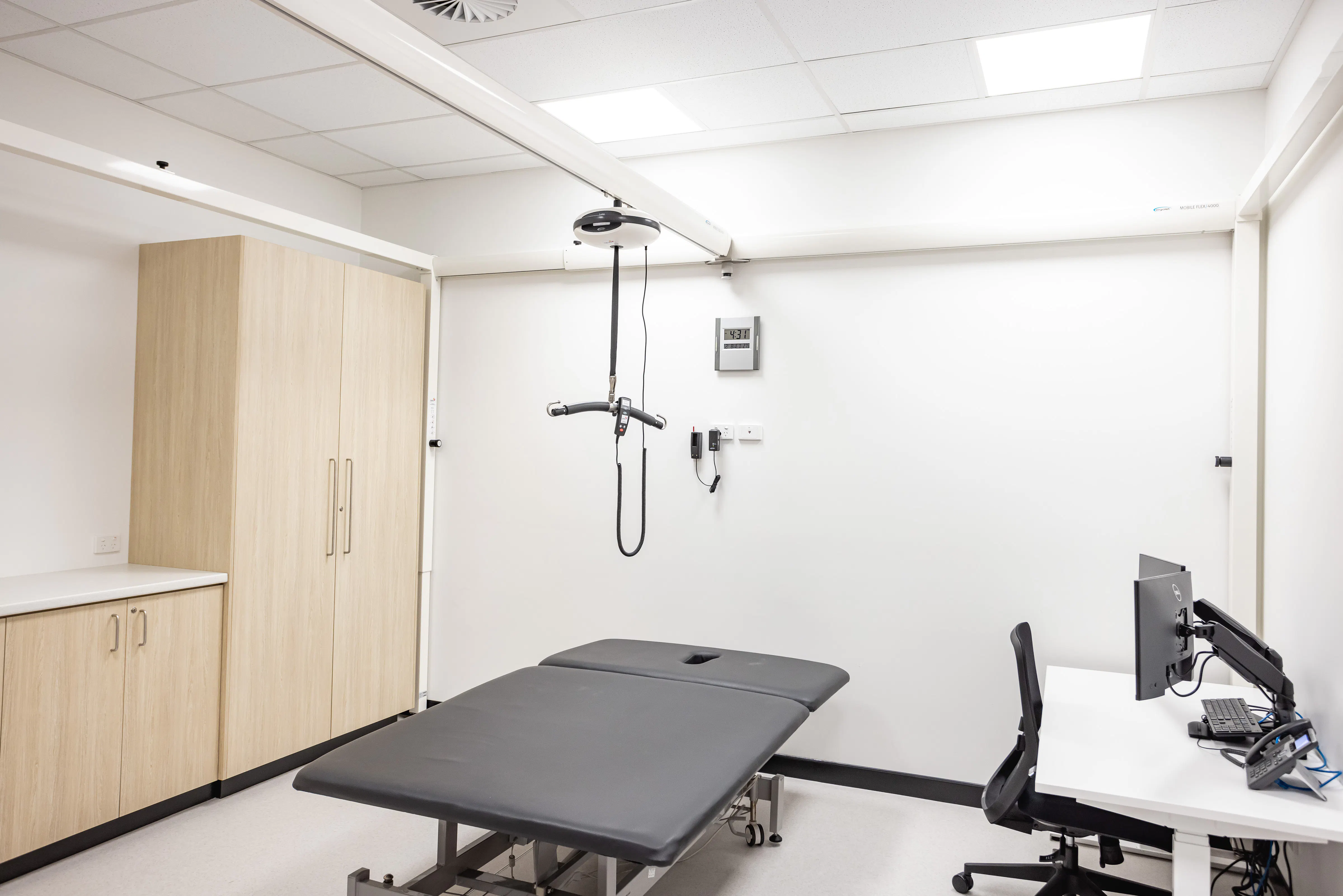 Flex Gantry ceiling hoist positioned over a treatment table in a clinical room.