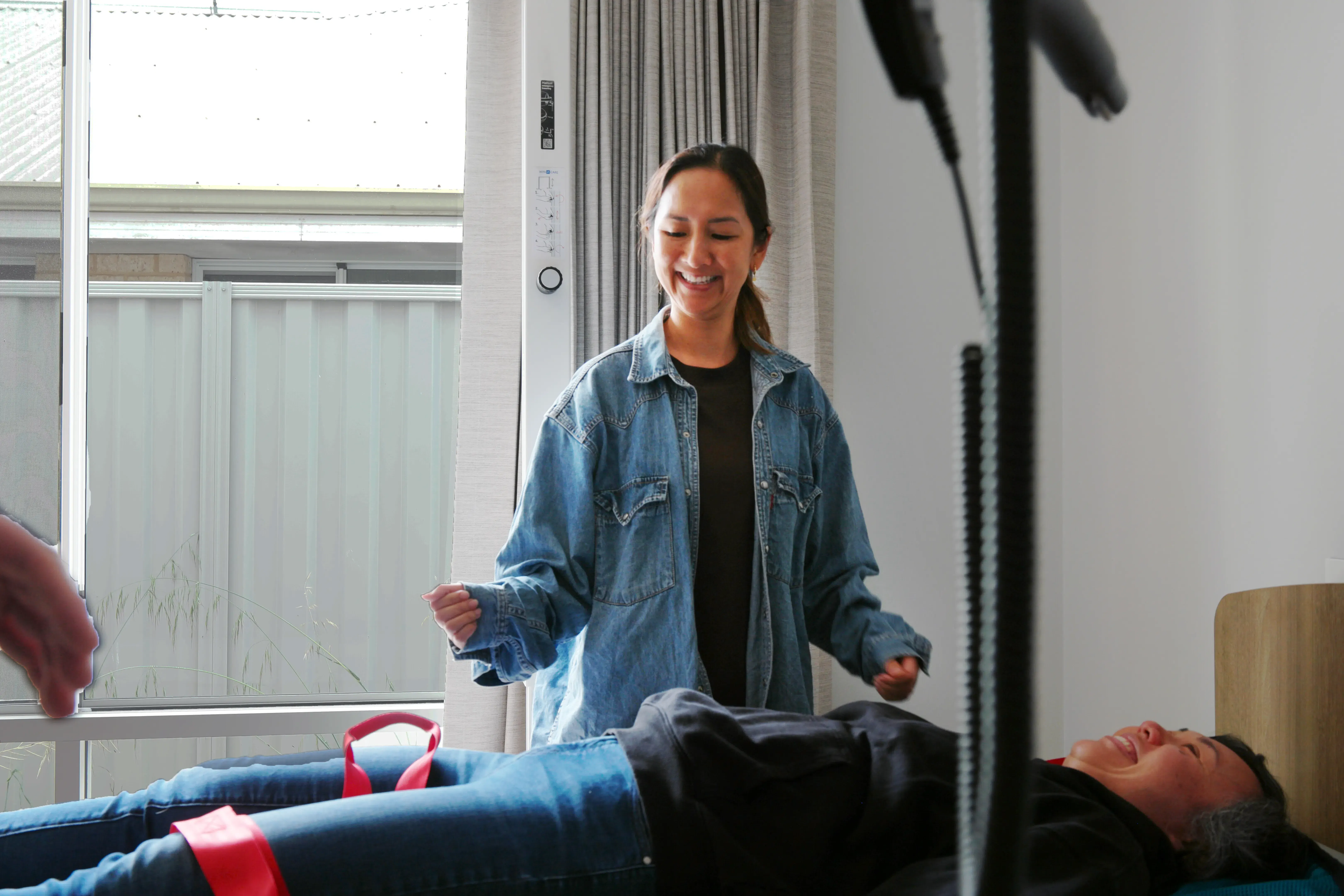 Participant positioning a sling under another participant during an assistive technology demonstration.