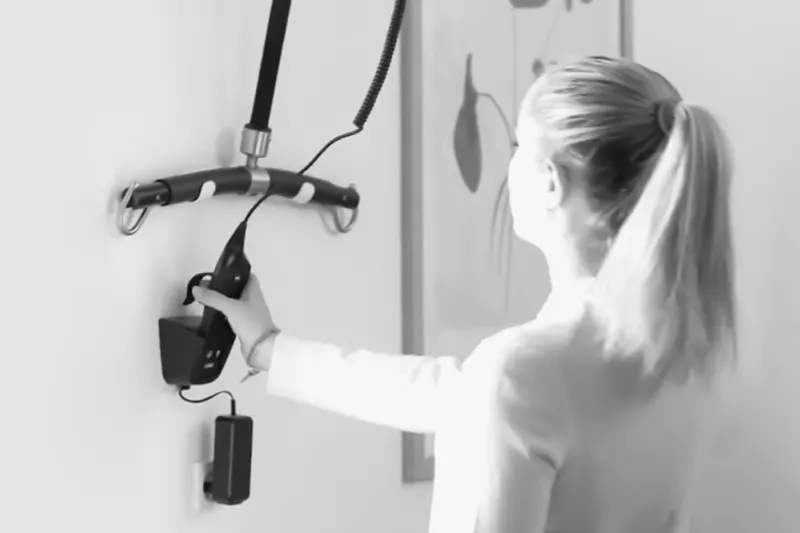 Woman operating the hand control of a ceiling hoist.
