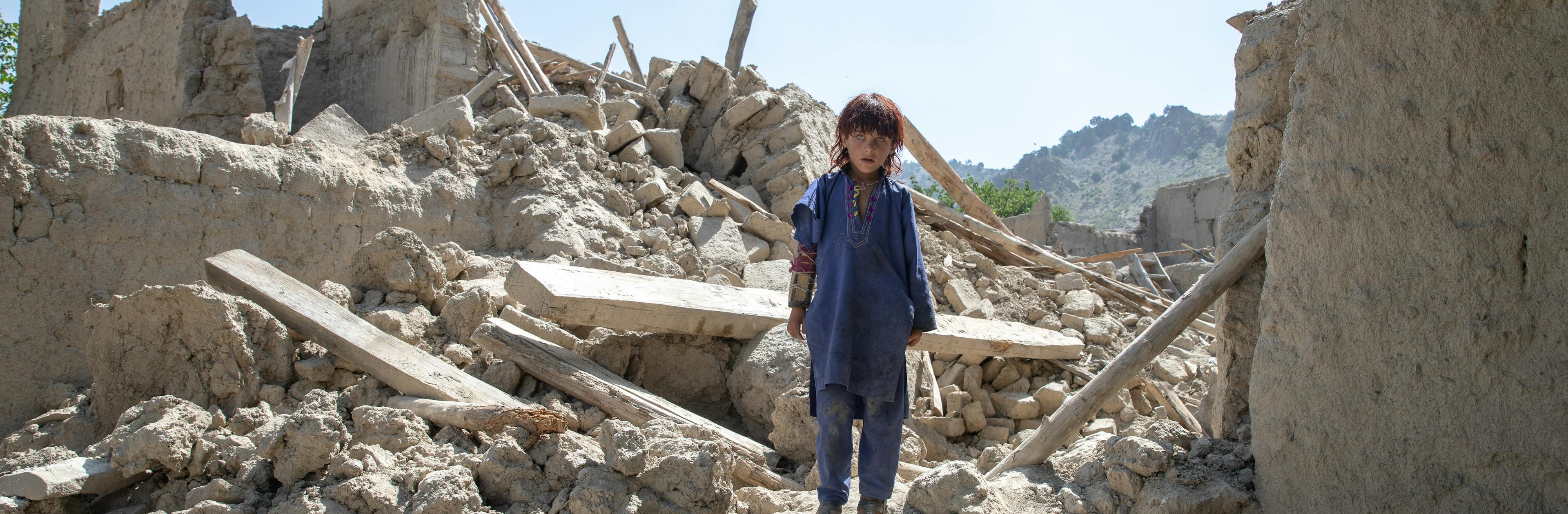 Zaid Allah, 6, stands in the rubble of his home where most of his family died as a result of the devastating earthquake on 22 June.