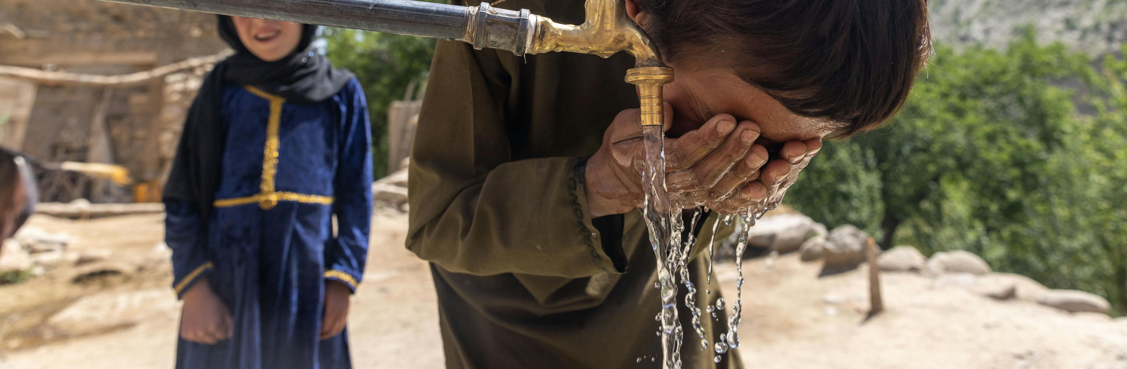 A young boy washing his face with clean water from a tap