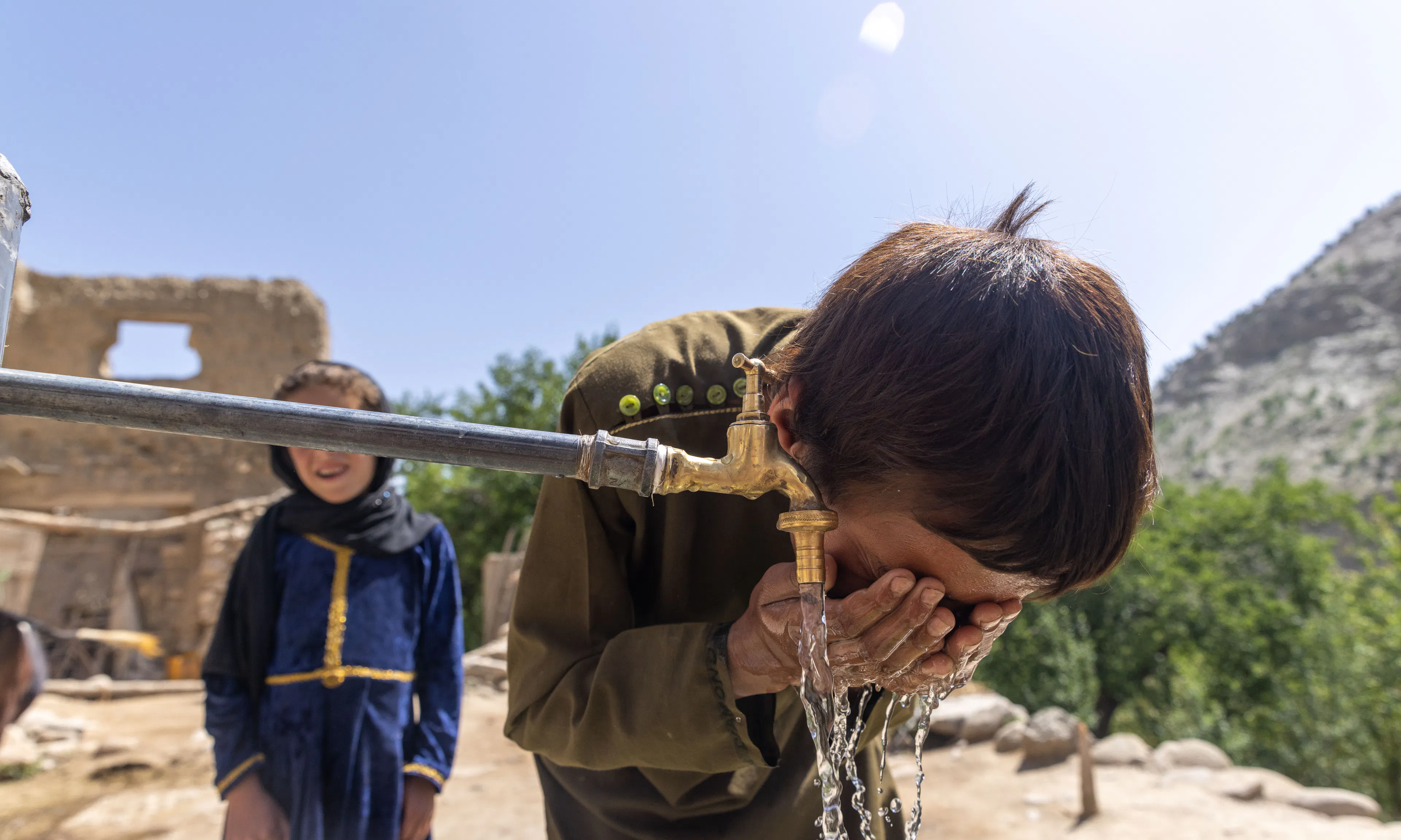 A young boy washing his face with clean water from a tap