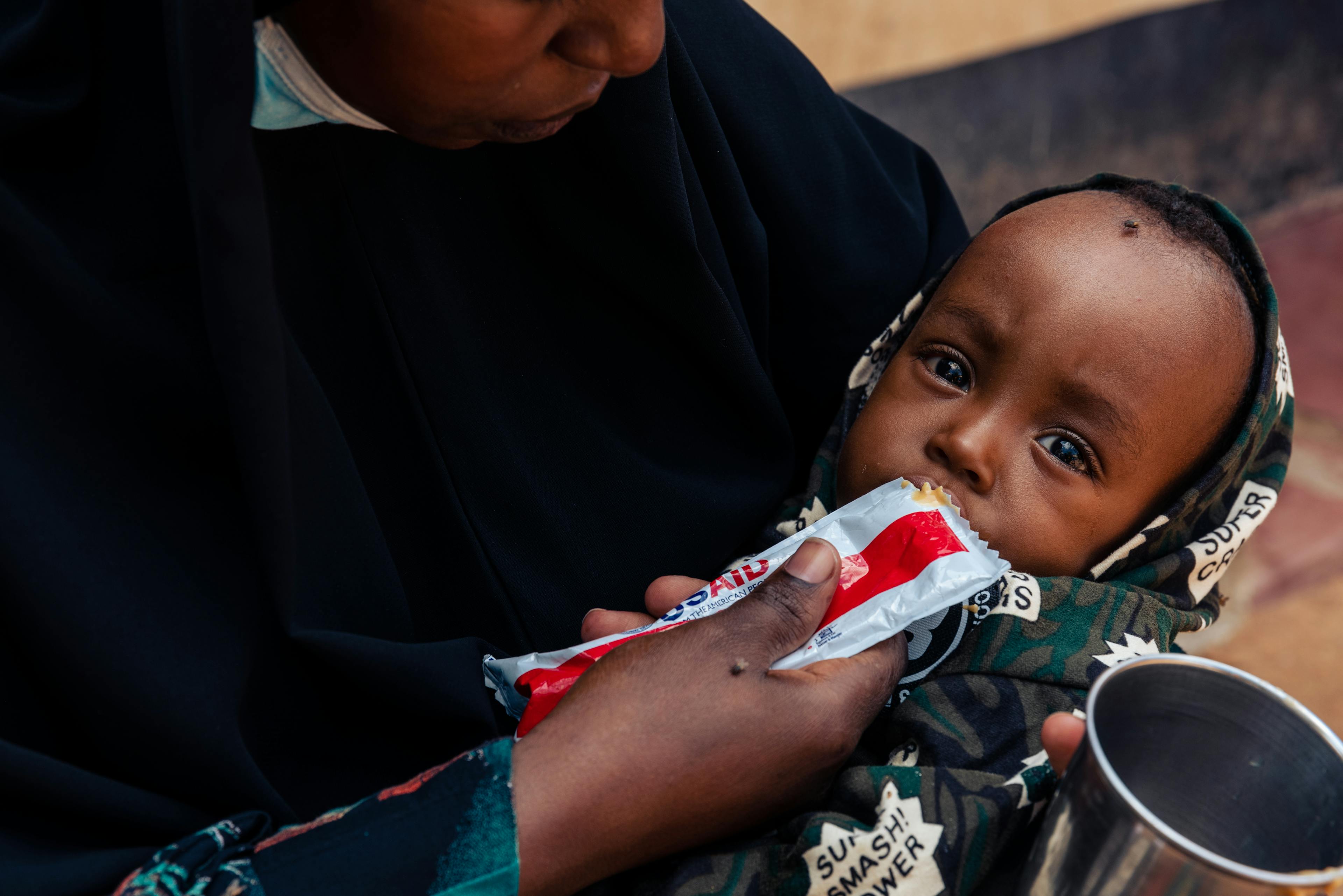 Garissa, 06 December 2022 - Mansour (1 year, four months) is fed RUTF by his mother. Earlier, the two were at the Iftin Community Hospital in Garissa (city), where they collected the week's ration of RUTF and where Mansour was measured and weighed to monitor his nutritional status.