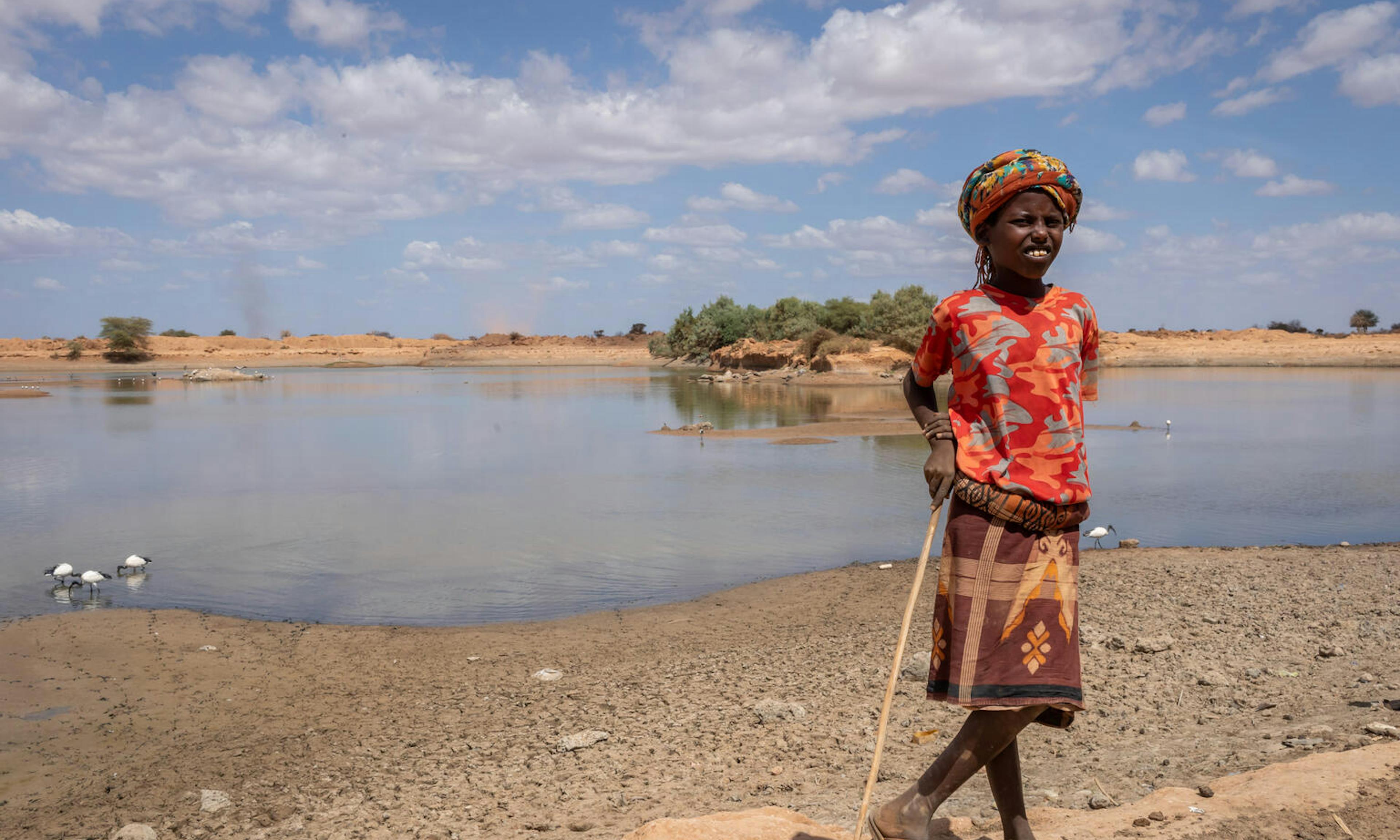 child stands in front of dirty water source
