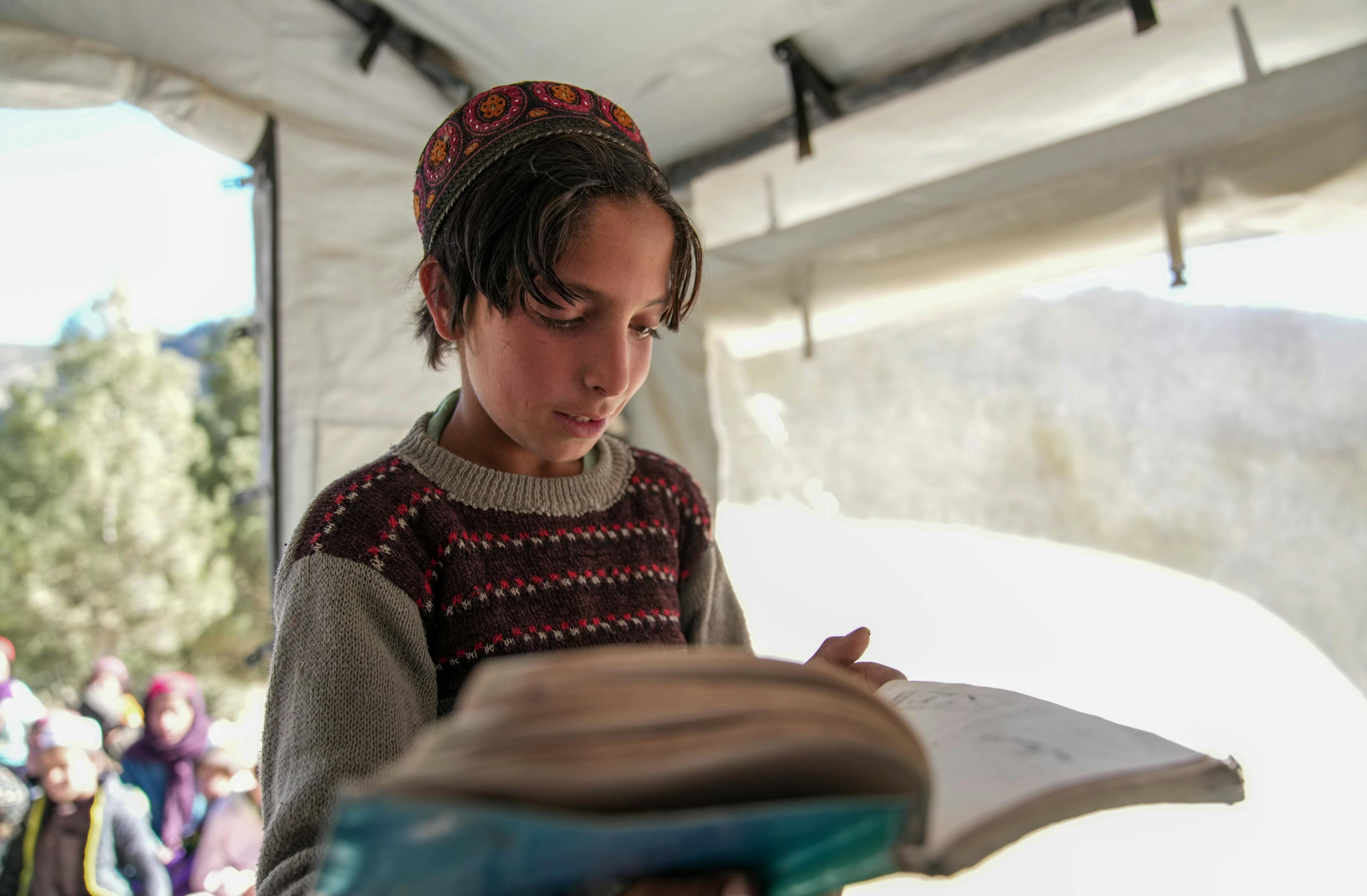 Emergency- 8-year-old Kefyatullah reads a story about the jungle while learning his local language, Pashto, in a UNICEF supported community education class in Spera District, Afghanistan.