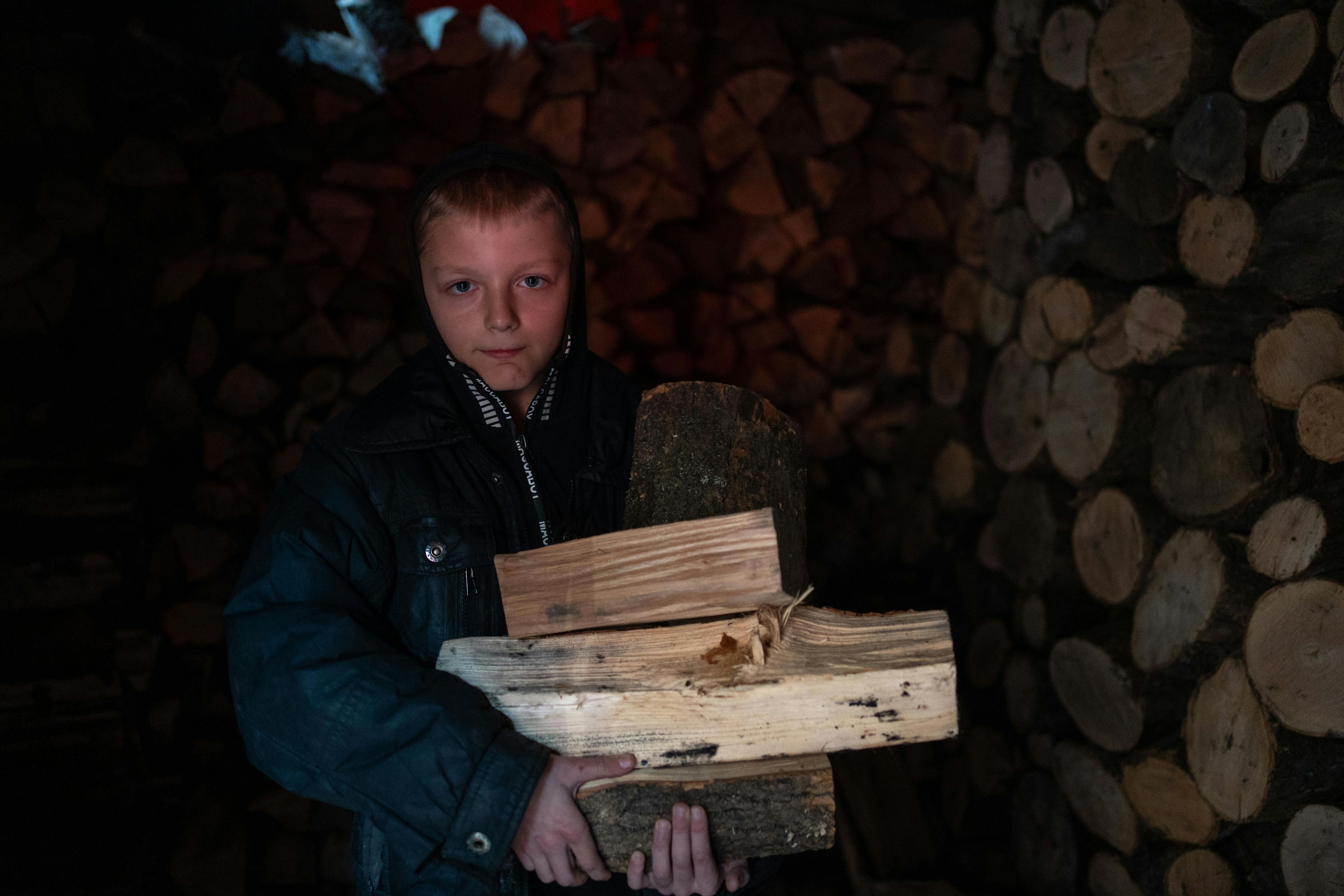 Ten-year-old Bohdan is holding firewood, Izyum, Ukraine.