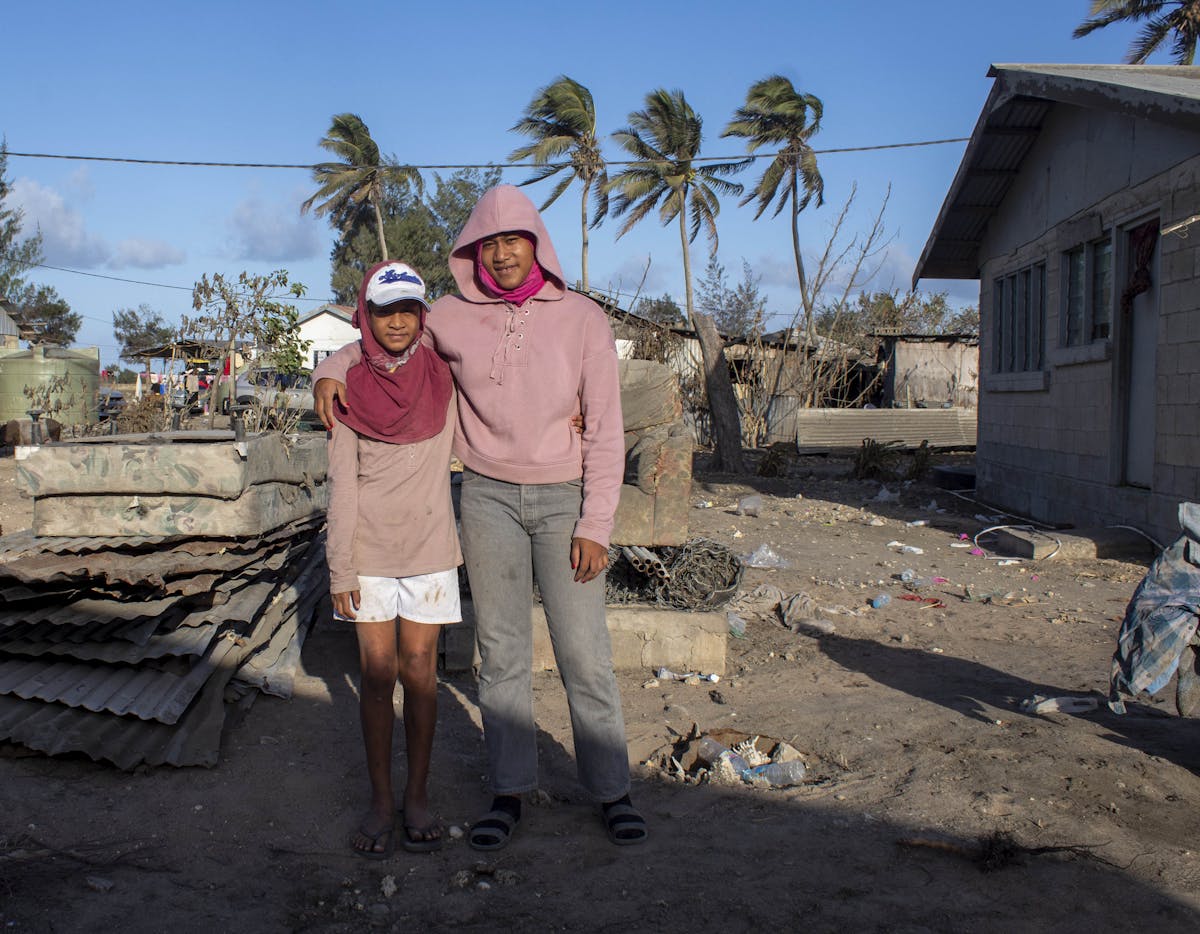 Two siblings stand in front of their home that was destroyed by the cyclone in Tonga