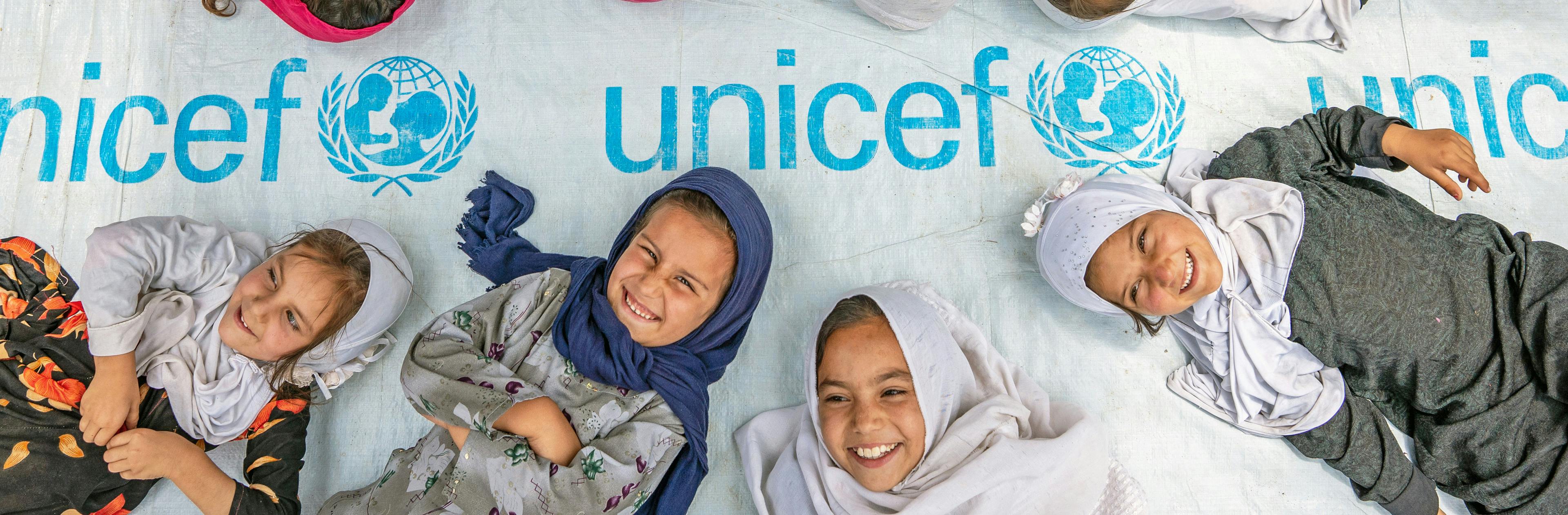 On 7th July 2022, girls pose at the entrance to a UNICEF-supported community-based education centre in Hijrat Mina in Bagrami District, Kabul Province, Afghanistan.