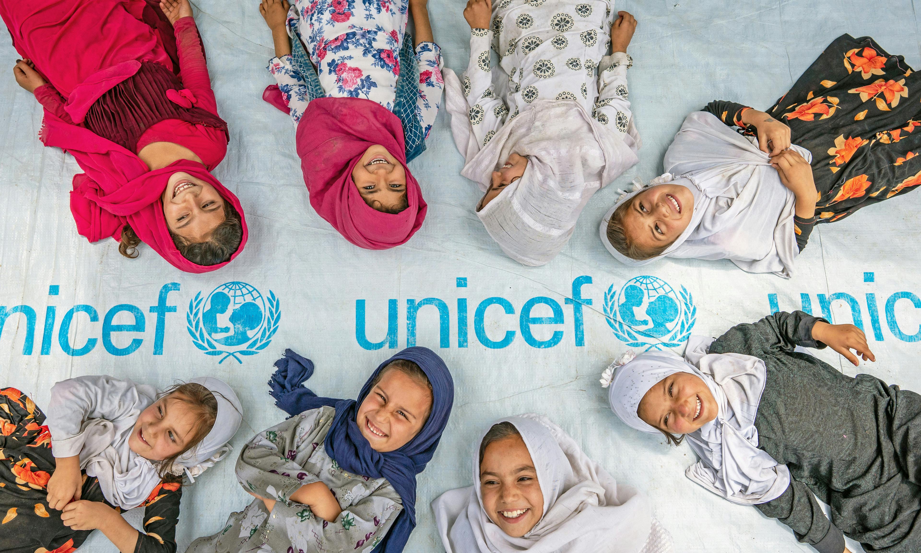 On 7th July 2022, girls pose at the entrance to a UNICEF-supported community-based education centre in Hijrat Mina in Bagrami District, Kabul Province, Afghanistan.