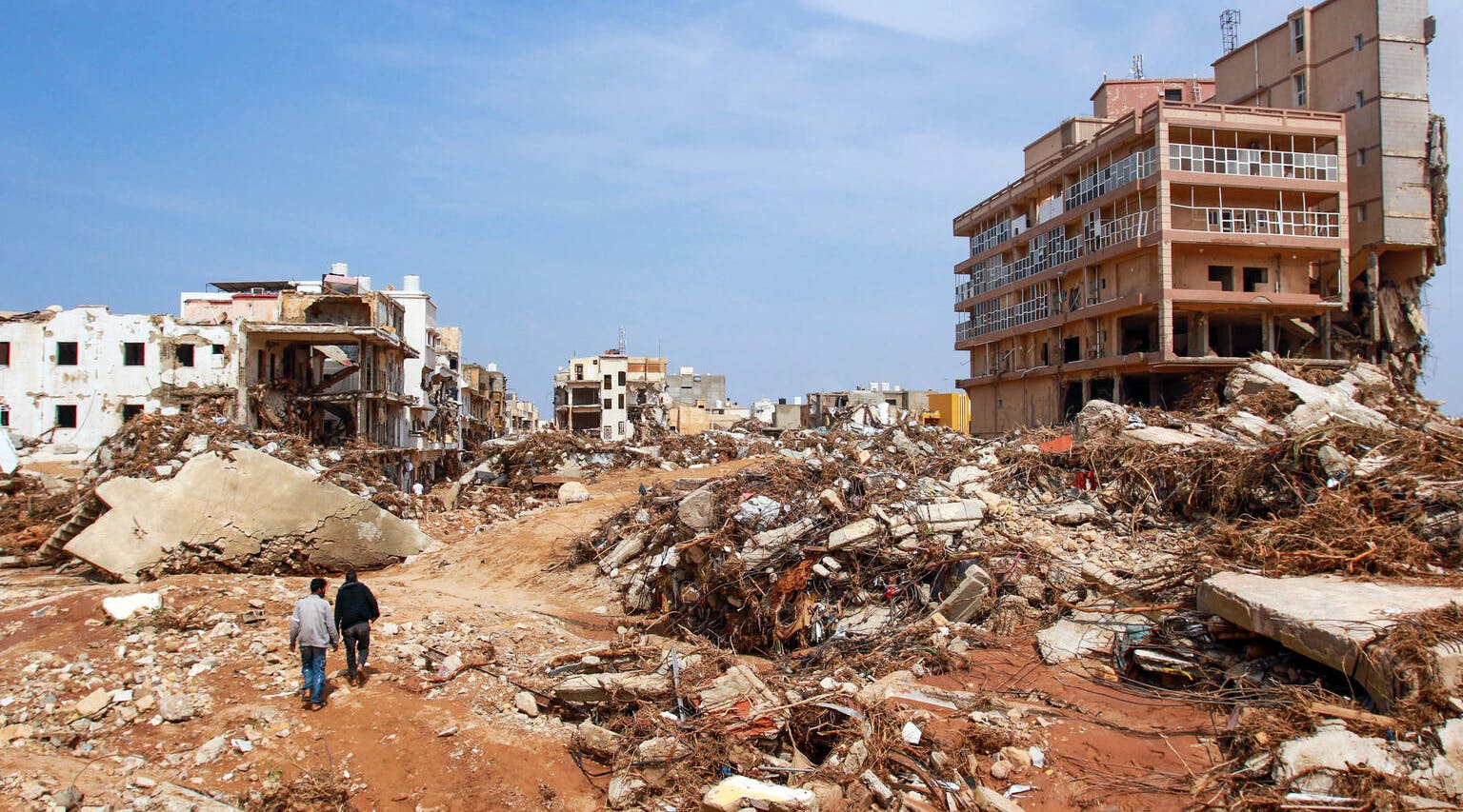 Men walk past debris of buildings caused by flash floods in Derna, eastern Libya. The floods on September 11, 2023 have killed more than 2,300 people.