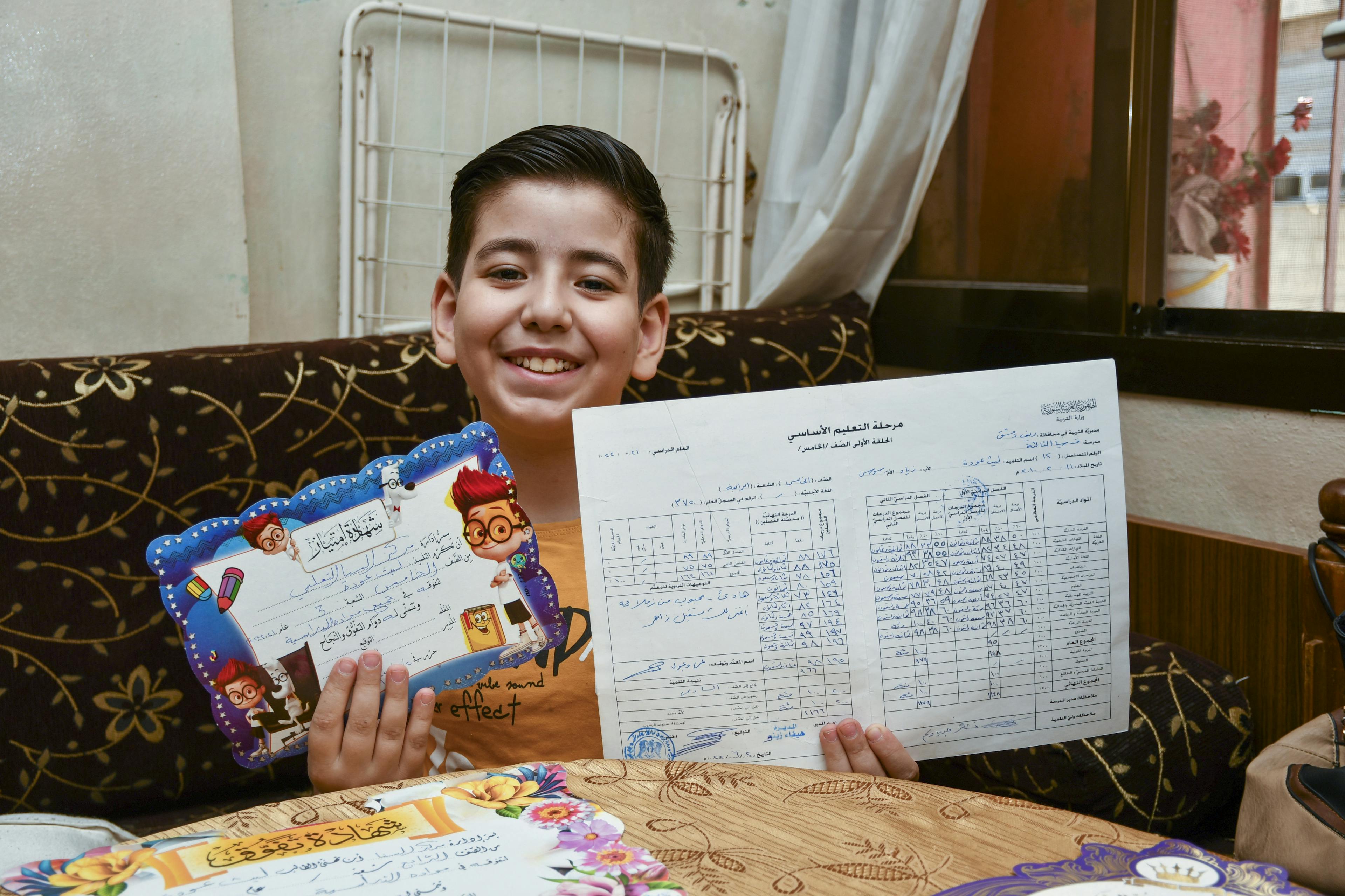 Laith proudly showing his excellent school grade report and certificates.