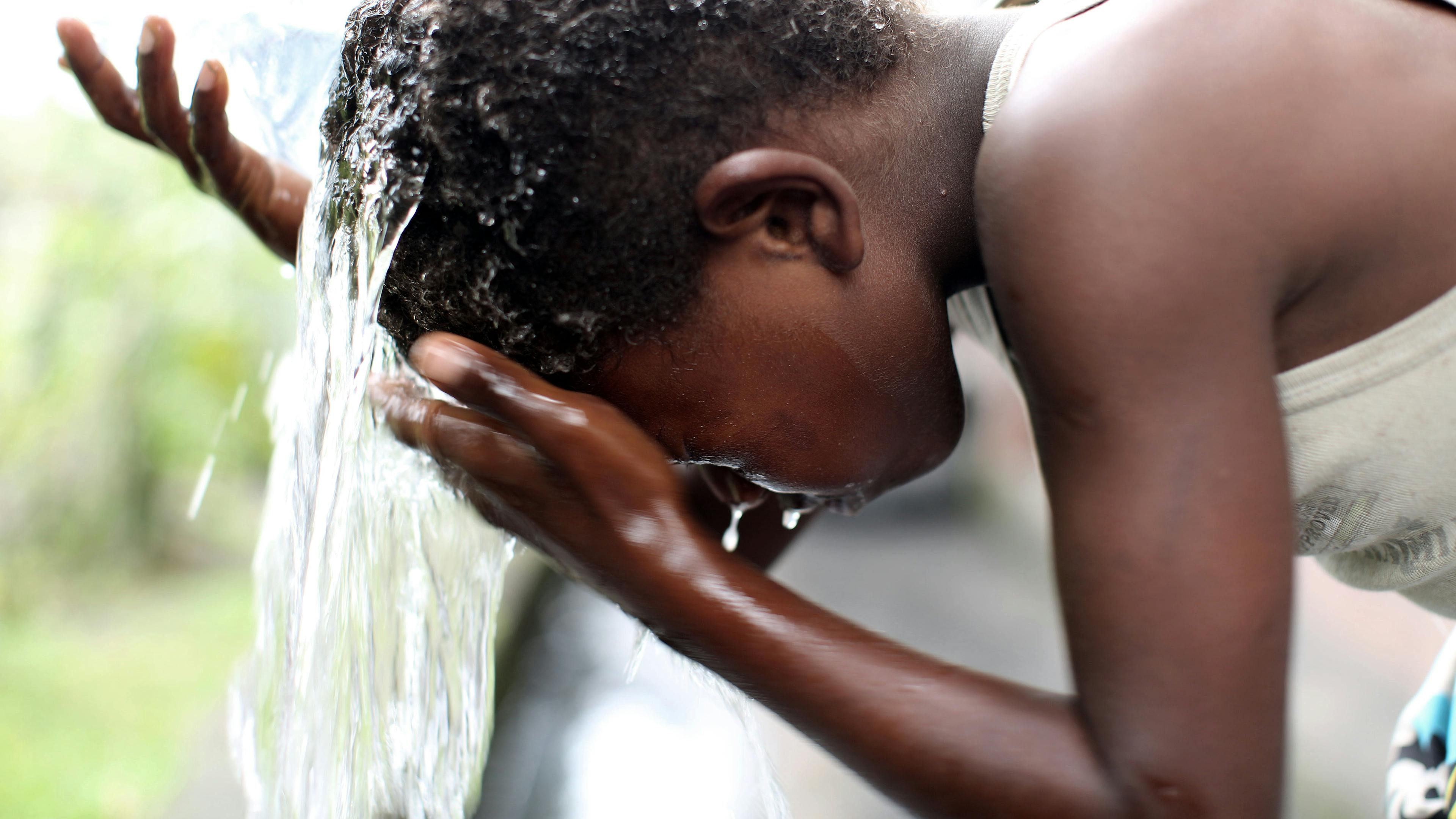 A young boy in the Pacific washes his face with clean water