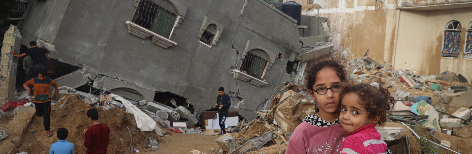 Abeer, 12-year-old, holds her sister, Zahra, 4-year-old, in front of her destroyedhouse in Rafah, southern the Gaza Strip.