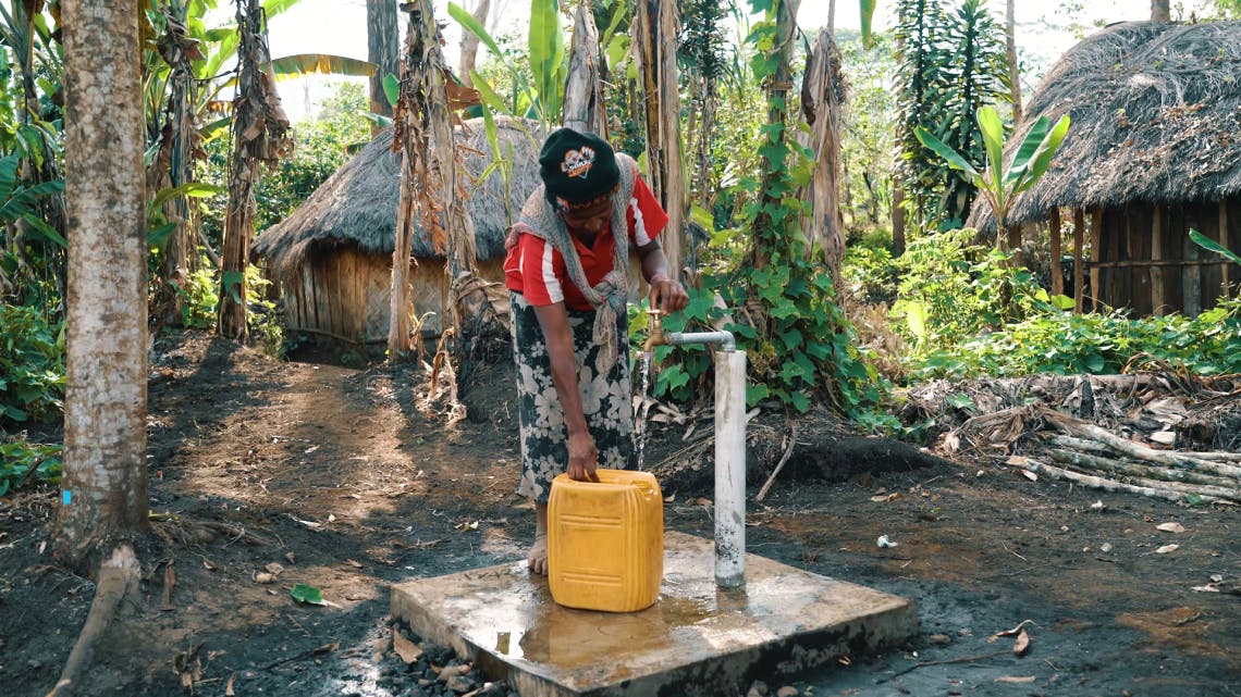 A woman drawing clean water from one of the new 14 community gravity-fed waterpoints.