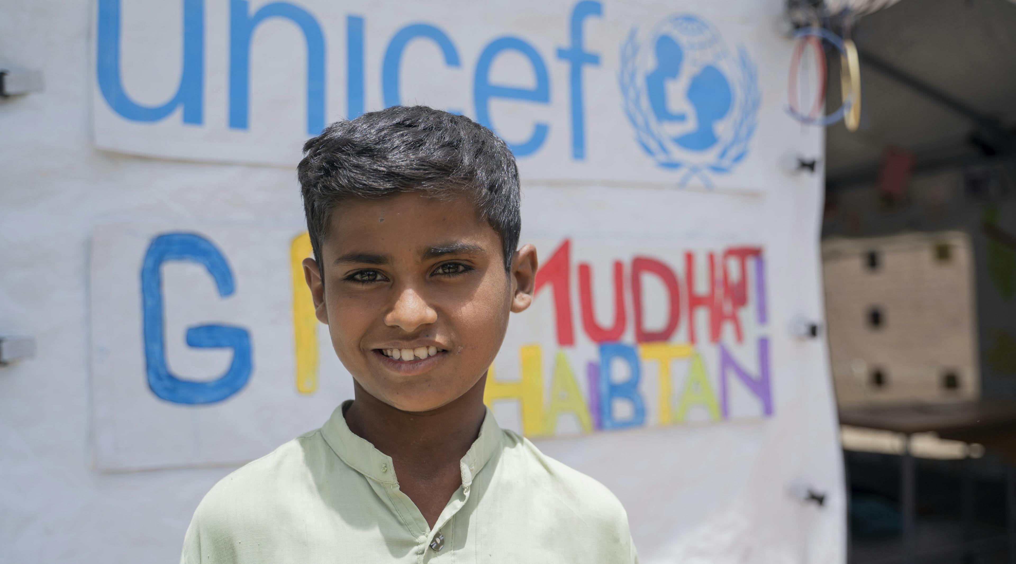 Muhammad Hasnain, 9 years old, standing outside the UNICEF temporary learning center in Basti Shahnawaz, District Rajanpur, Punjab wearing a bright smile.