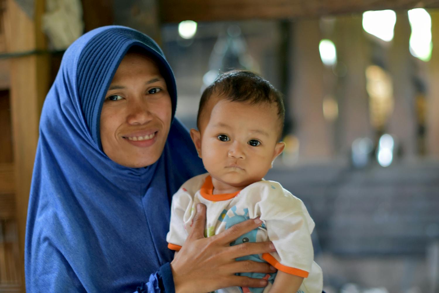 Mother Sarifah and Luthfi in the family home at Pandere Village in Sigi, Central Sulawesi smiling at the camera