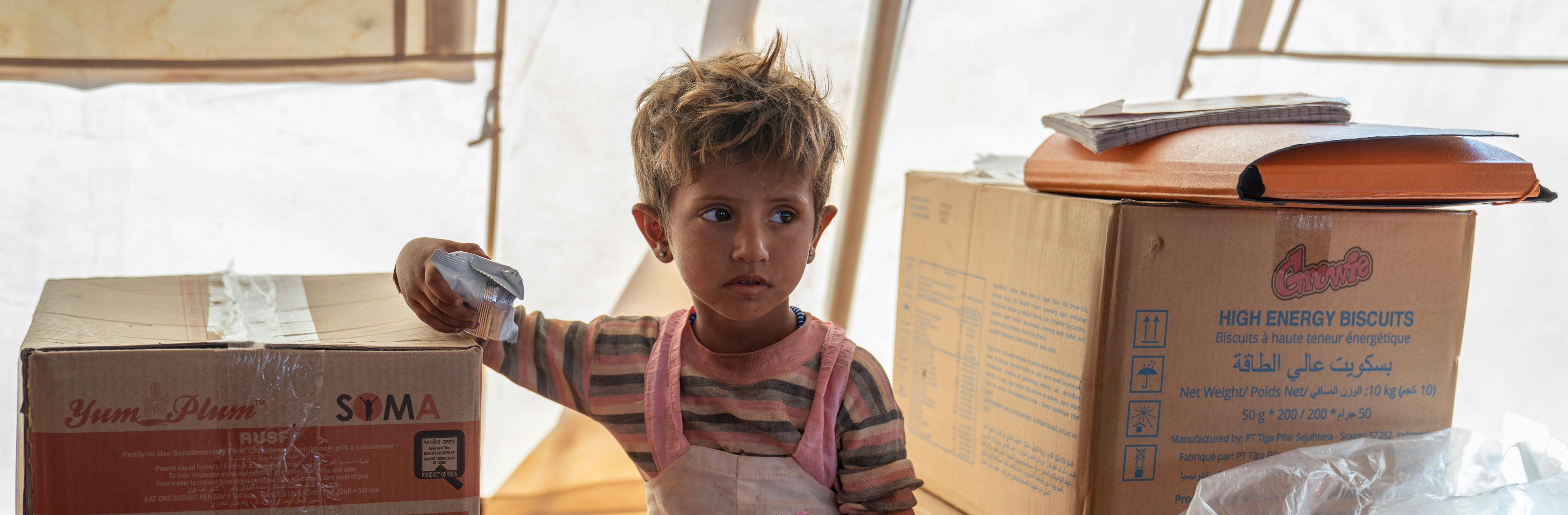 Nour, 2, holds high energy biscuits, during checkup at the UNICEF mobile health clinic, in Al-Zhuriah makeshift camp, Rural Homs, Syria, on 27 September 2022.