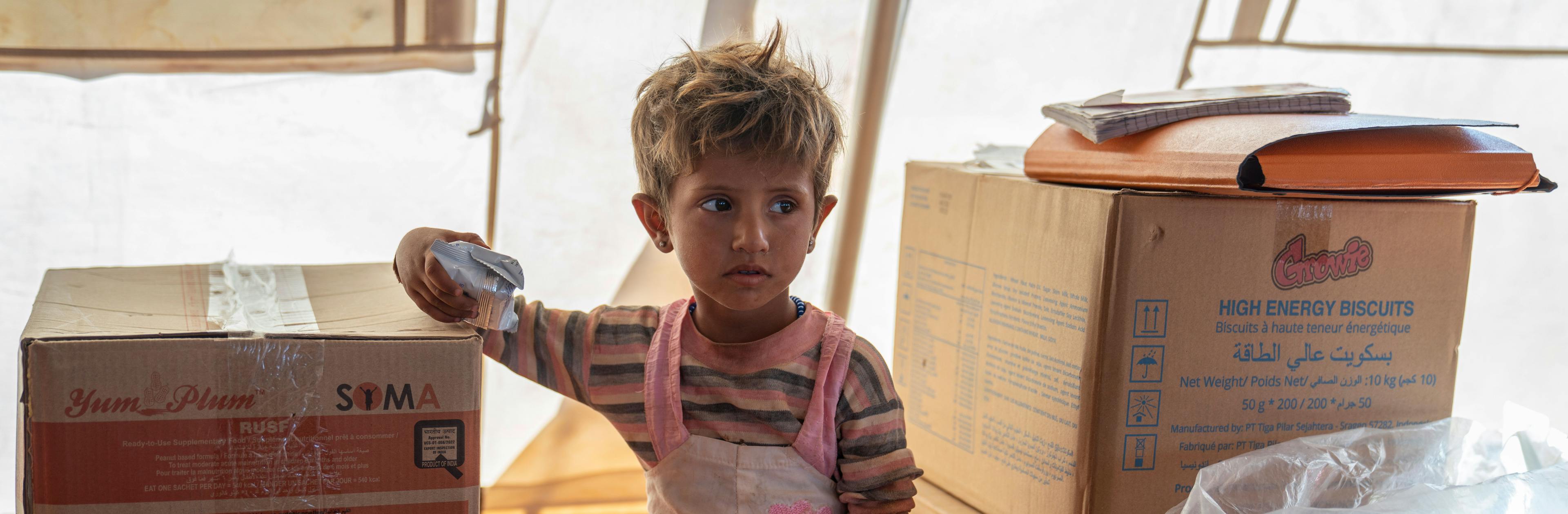 Nour, 2, holds high energy biscuits, during checkup at the UNICEF mobile health clinic, in Al-Zhuriah makeshift camp, Rural Homs, Syria, on 27 September 2022.